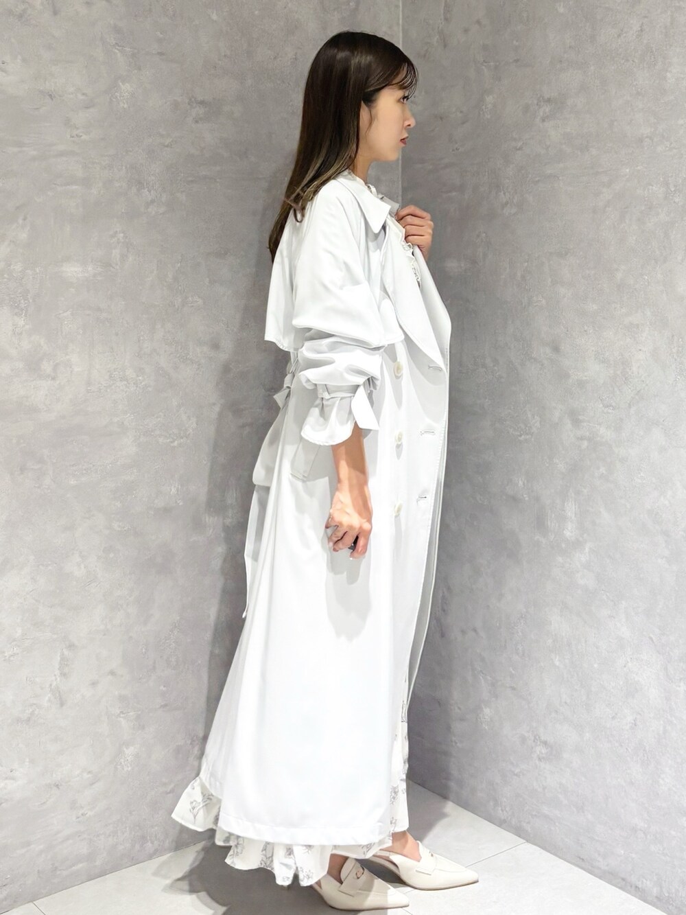 ホワイト系のワンピース、ホワイト系のパンプス、グレー系のトレンチコートを着用したレディースの春コーディネートの3枚目の写真