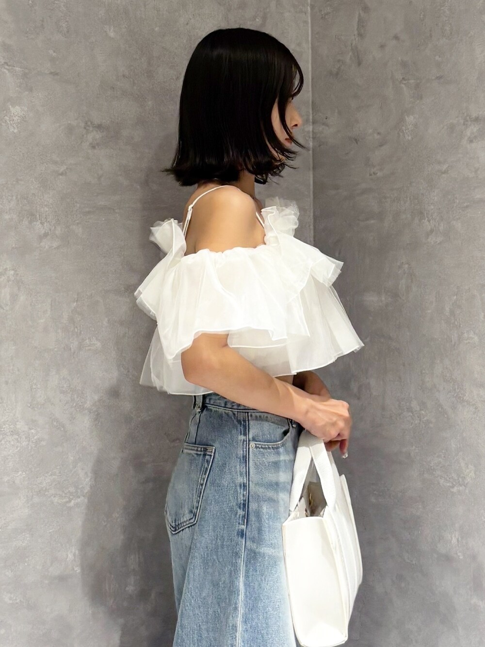 ブルー系のデニムパンツ、ブラウン系のサンダル、ホワイト系のトートバッグを着用したレディースの春コーディネートの5枚目の写真