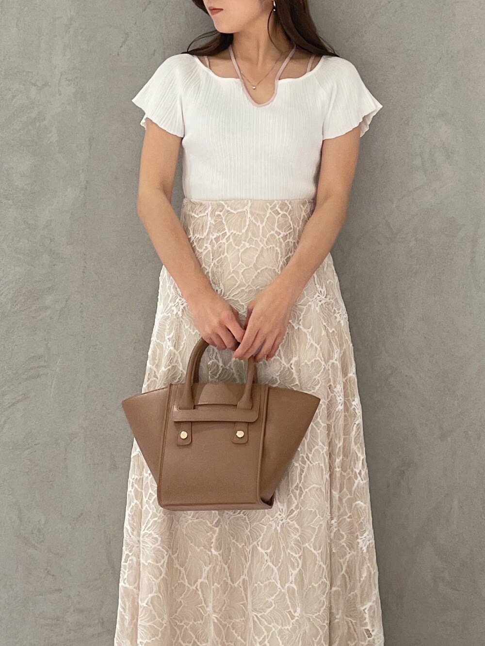 ブラウン系のトートバッグ、ホワイト系のニット/セーター、ベージュ系のスカートを着用したレディースの夏コーディネートの4枚目の写真