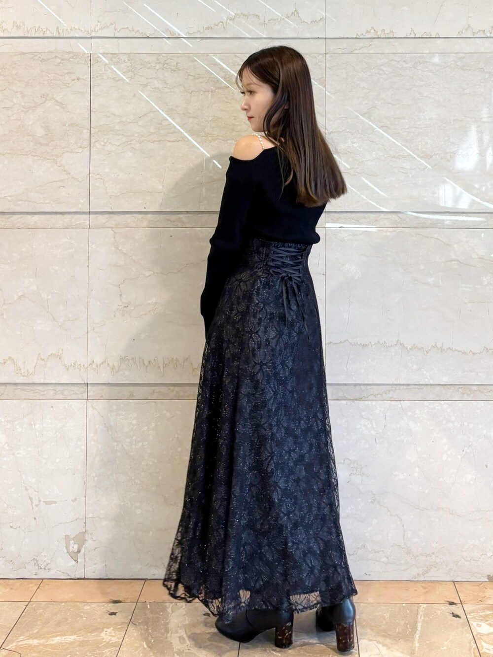 ブラック系のスカート、ブラック系のニット/セーター、ブラック系のブーツを着用したレディースの冬コーディネートの5枚目の写真