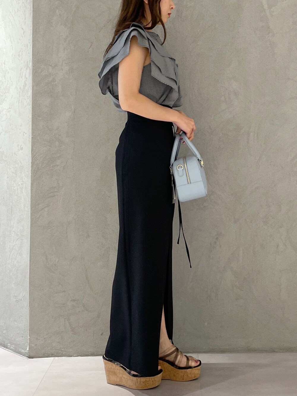 ブラック系のスカート、ブラック系のサンダル、ブルー系のボストンバッグを着用したレディースの春コーディネートの6枚目の写真