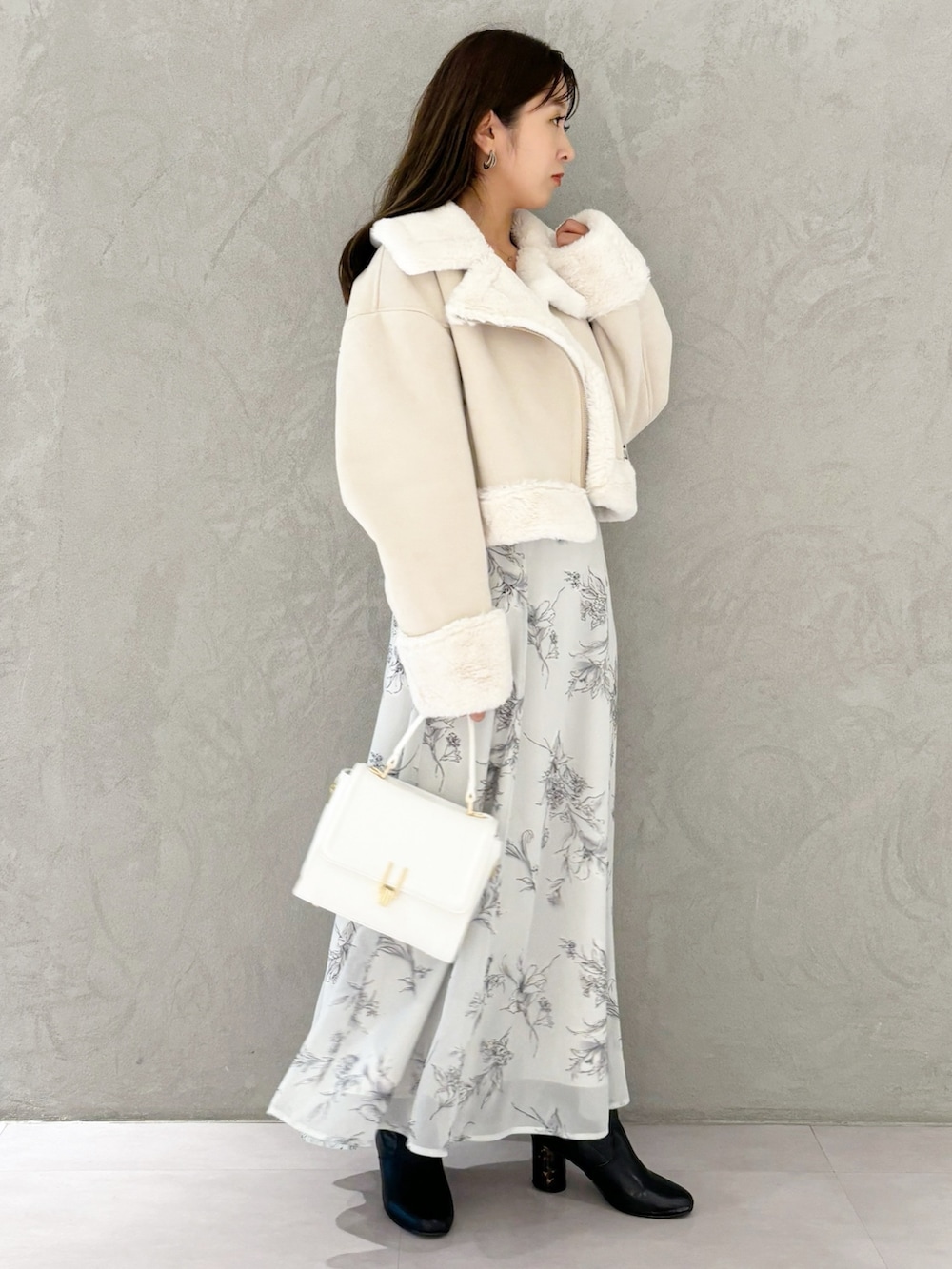 ブラック系のワンピース、ブラック系のブーツ、ホワイト系のハンドバッグを着用したレディースの秋コーディネートの2枚目の写真