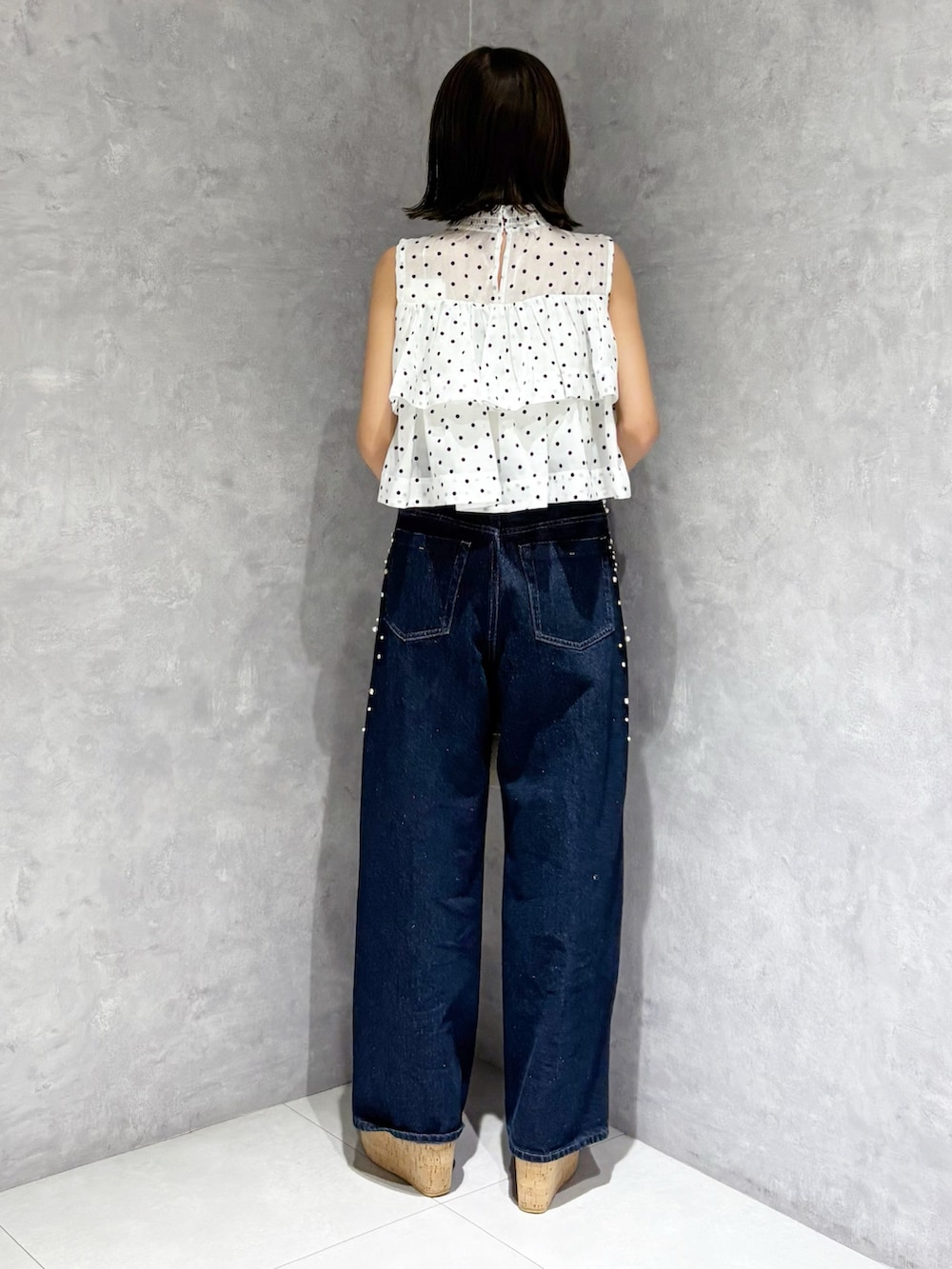 ブルー系のデニムパンツ、ブラウン系のサンダル、ホワイト系のハンドバッグを着用したレディースの夏コーディネートの4枚目の写真