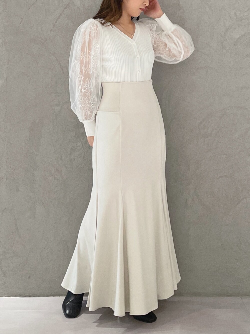 ホワイト系のスカート、ホワイト系のカーディガン/ボレロ、ブラック系のブーツを着用したレディースの冬コーディネートの3枚目の写真