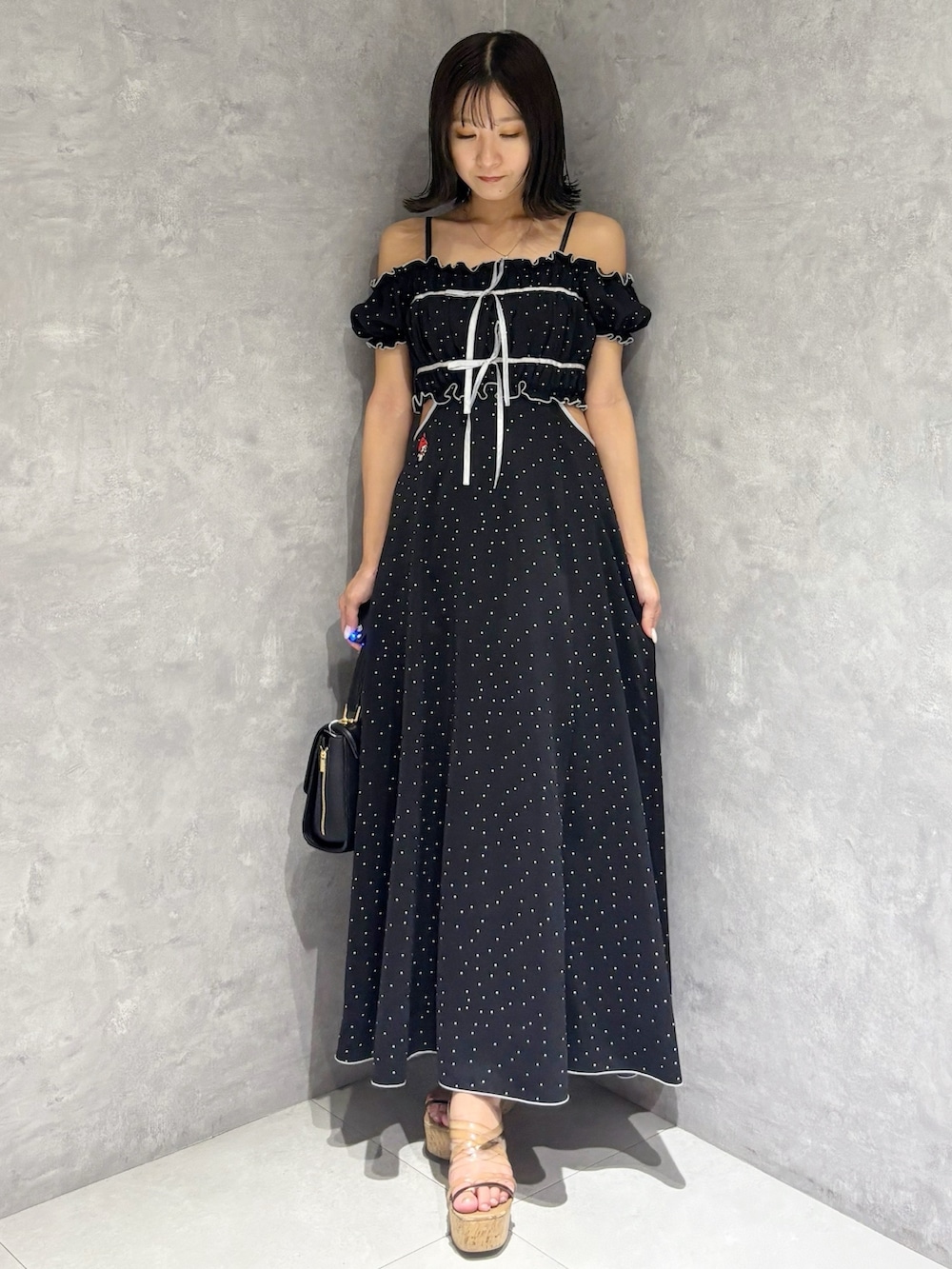 ブラック系のワンピース、ブラウン系のサンダル、ブラック系のショルダーバッグを着用したレディースの春コーディネートの5枚目の写真