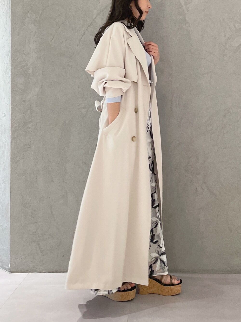 ホワイト系のスカート、ブルー系のニット/セーター、ホワイト系のトレンチコートを着用したレディースの春コーディネートの2枚目の写真