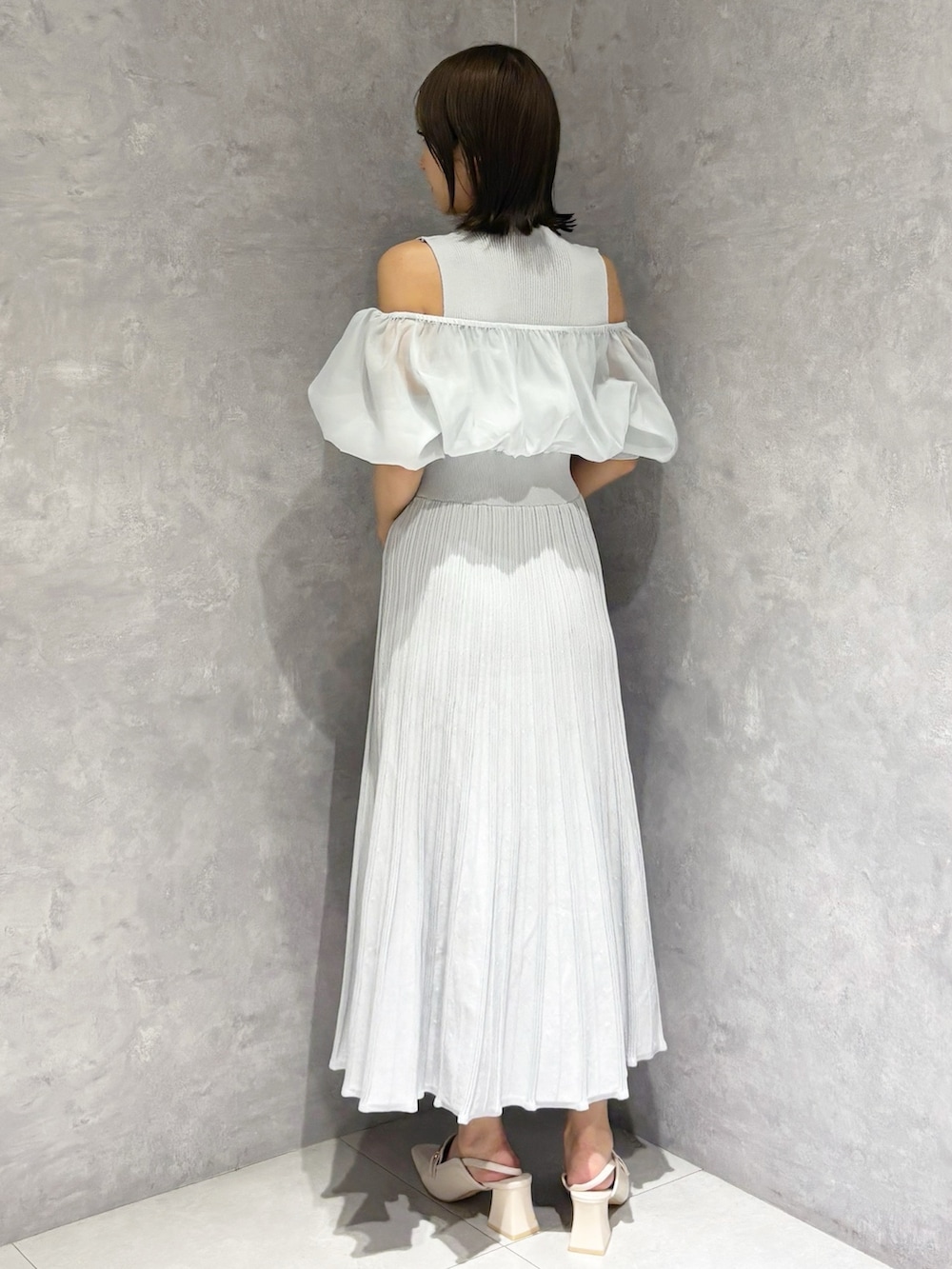 グレー系のワンピース、ホワイト系のパンプス、ブラウン系のハンドバッグを着用したレディースの春コーディネートの4枚目の写真