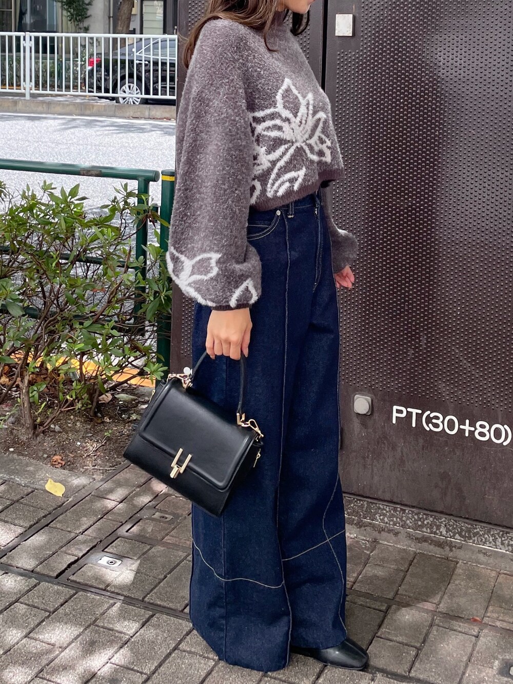 ブラック系のショルダーバッグ、グレー系のニット/セーター、ブルー系のデニムパンツを着用したレディースの秋コーディネートの3枚目の写真