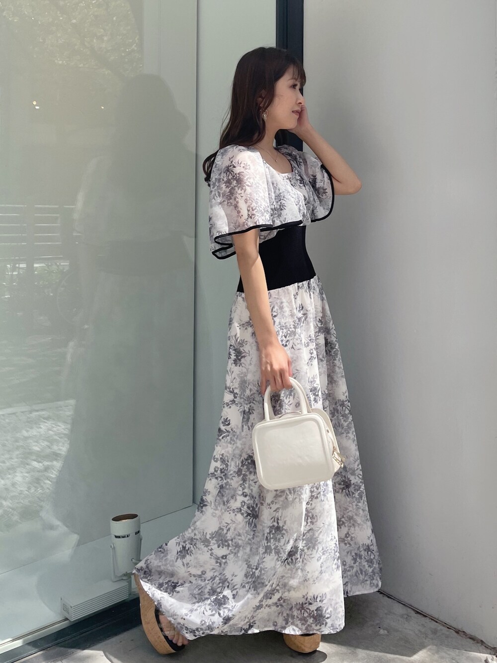 ブラック系のサンダル、ホワイト系のハンドバッグ、ホワイト系のワンピースを着用したレディースの春コーディネートの5枚目の写真