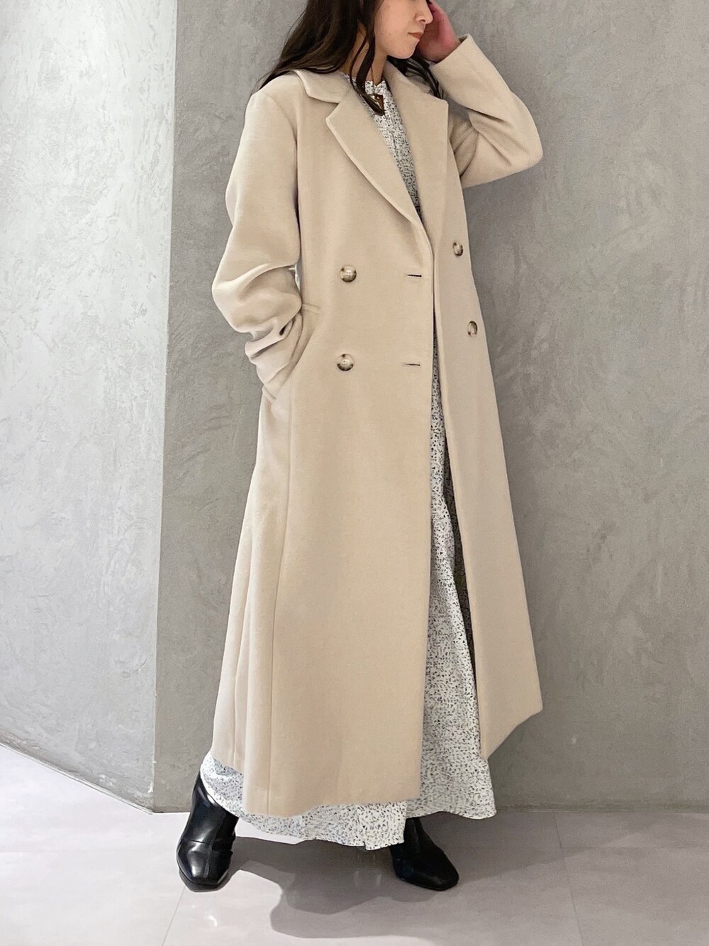 ホワイト系のワンピース、ベージュ系のチェスターコート、ブラック系のブーツを着用したレディースの秋コーディネートの4枚目の写真