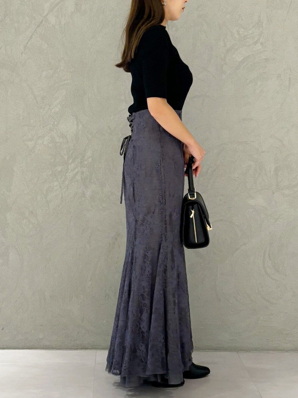 グレー系のスカート、ブラック系のブーツ、ブラック系のショルダーバッグを着用したレディースの秋コーディネートの4枚目の写真