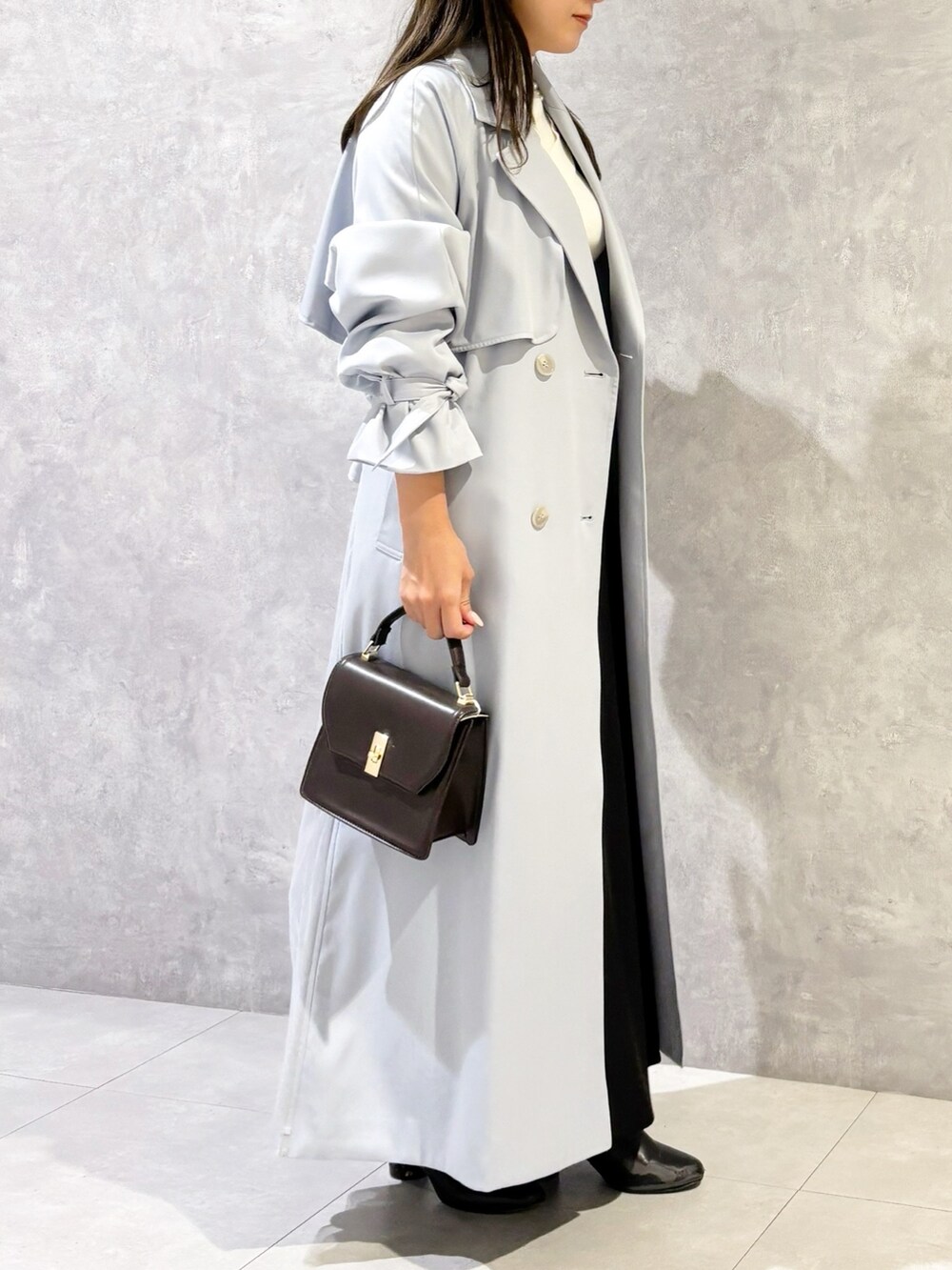 ブラック系のスカート、ブラック系のブーツ、ブラウン系のハンドバッグを着用したレディースの冬コーディネートの2枚目の写真