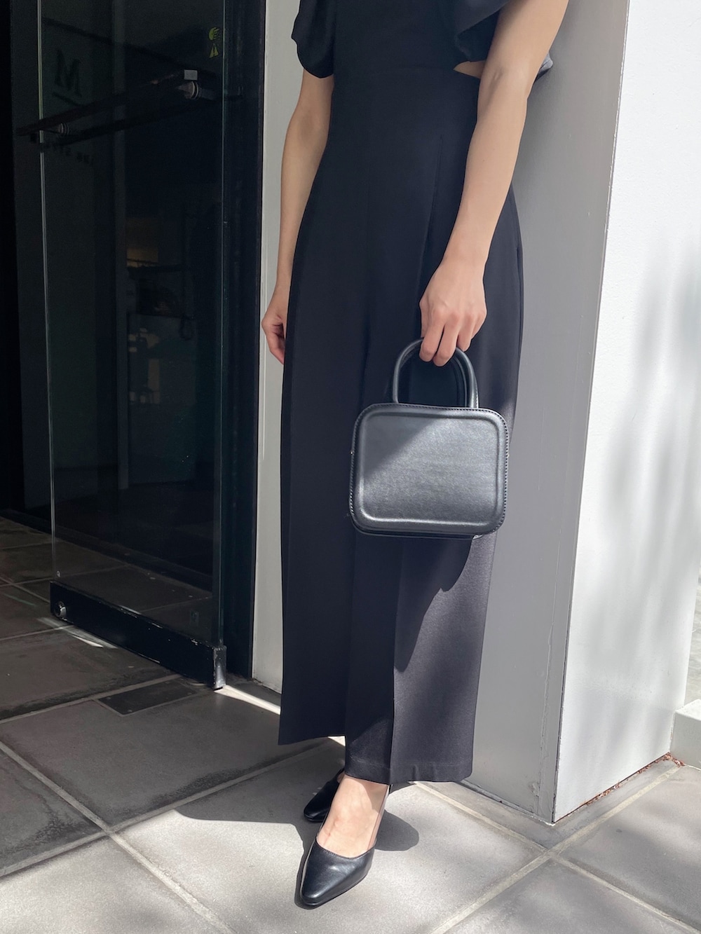 ブラック系のハンドバッグ、ブラック系のパンプス、ブラック系のつなぎ/オールインワンを着用したレディースの春コーディネートの4枚目の写真