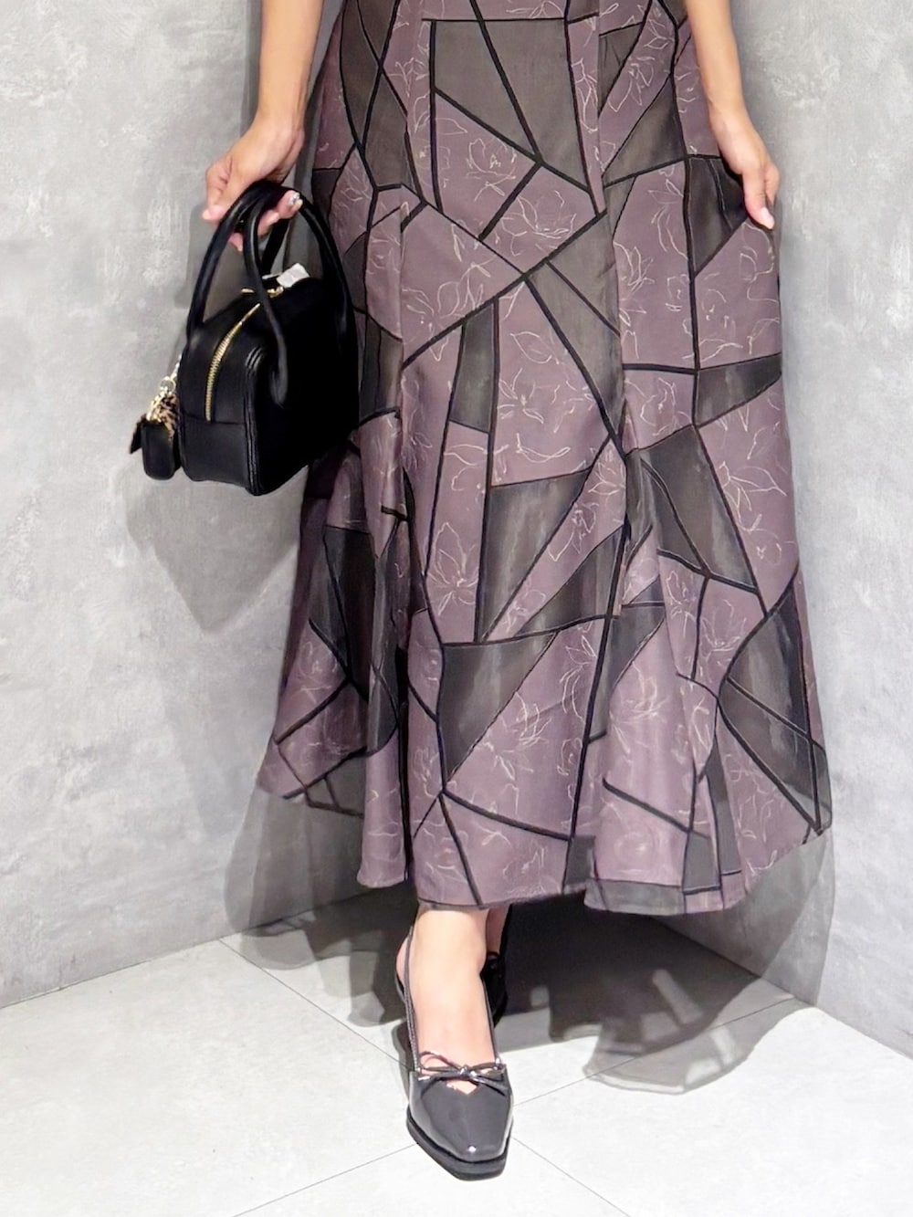 ブラウン系のスカート、ブラック系のハンドバッグ、ブラック系のニット/セーターを着用したレディースの夏コーディネートの6枚目の写真