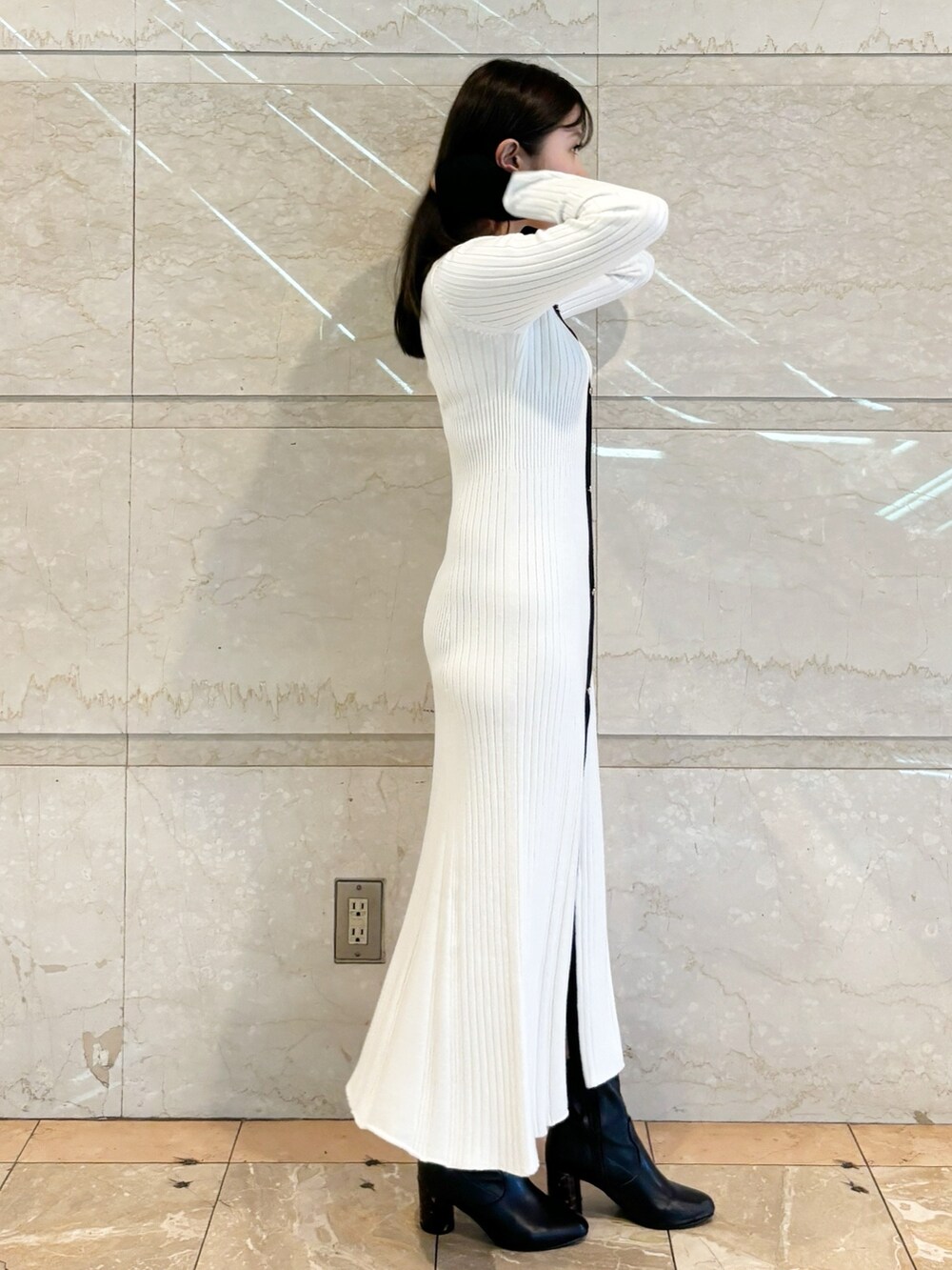 ホワイト系のワンピース、ブラック系のブーツを着用したレディースの冬コーディネートの2枚目の写真