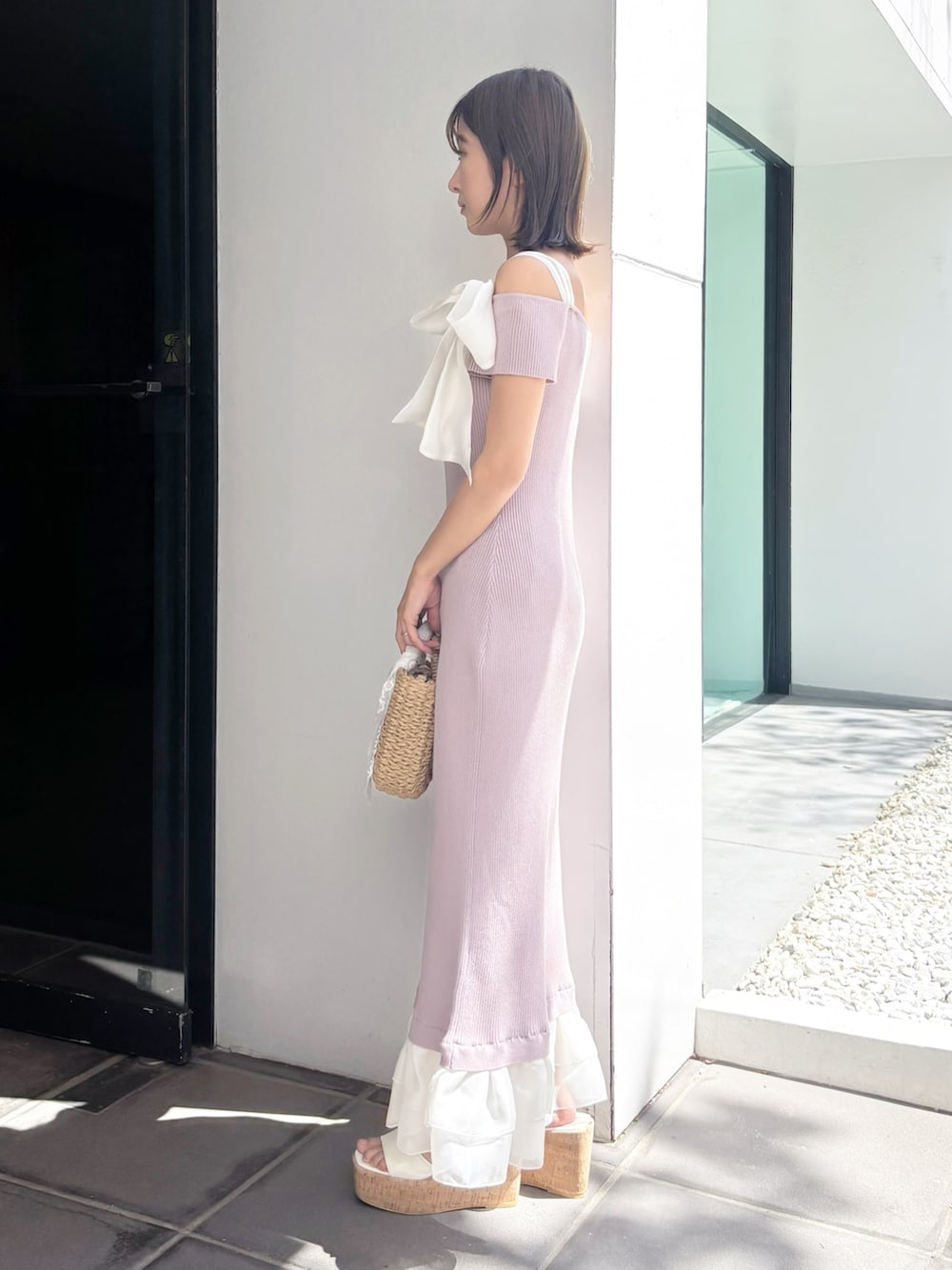 ピンク系のワンピース、ベージュ系のハンドバッグ、ホワイト系のサンダルを着用したレディースの夏コーディネートの5枚目の写真