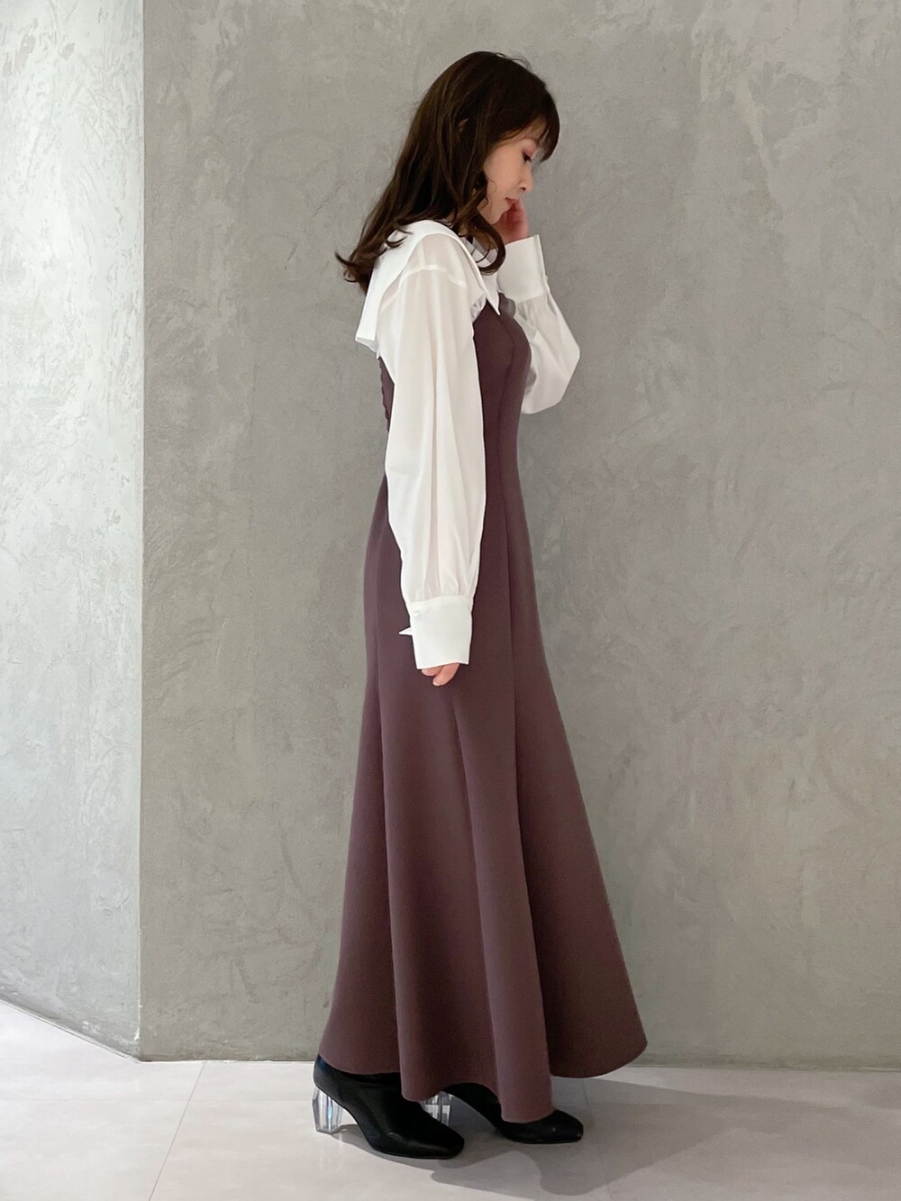 パープル系のワンピース、ブラック系のブーツ、ホワイト系のトレンチコートを着用したレディースの冬コーディネートの5枚目の写真