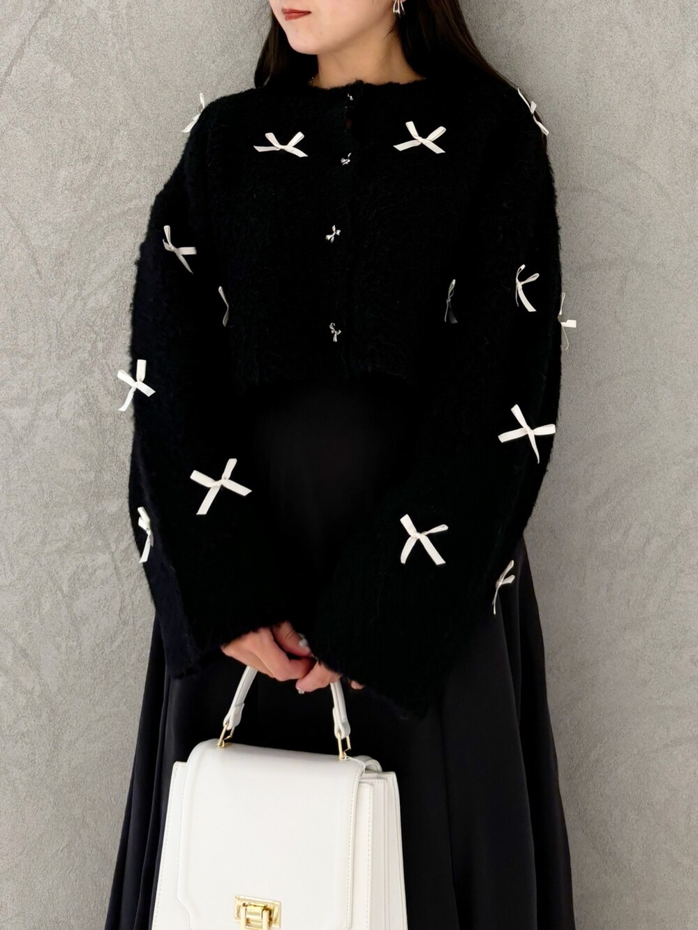 ブラック系のスカート、ブラック系のブーツ、ホワイト系のハンドバッグを着用したレディースの冬コーディネートの4枚目の写真