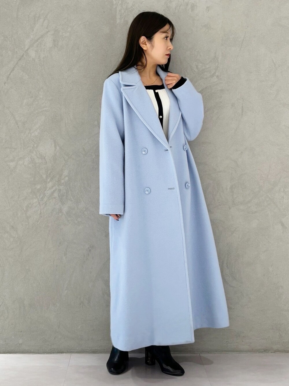 ブルー系のチェスターコート、ブラック系のブーツ、ホワイト系のワンピースを着用したレディースの冬コーディネートの6枚目の写真