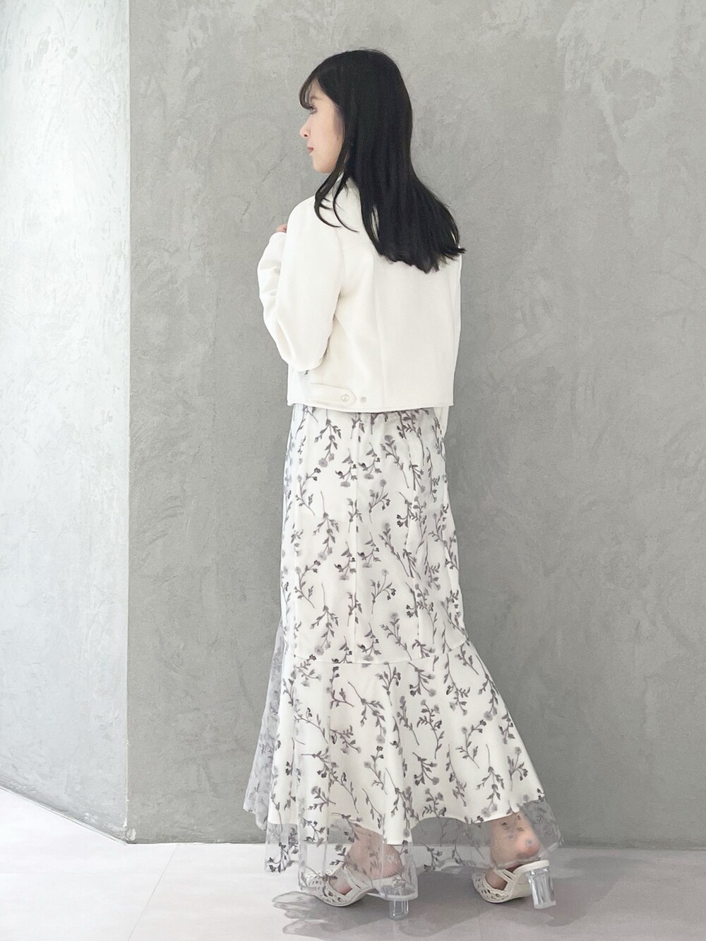 グレー系のワンピース、ホワイト系のパンプス、ホワイト系のライダースジャケットを着用したレディースの春コーディネートの2枚目の写真