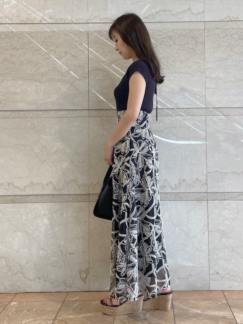 ブラック系のスカート、ブラック系のサンダル、ブラック系のトートバッグを着用したレディースの夏コーディネートの7枚目の写真