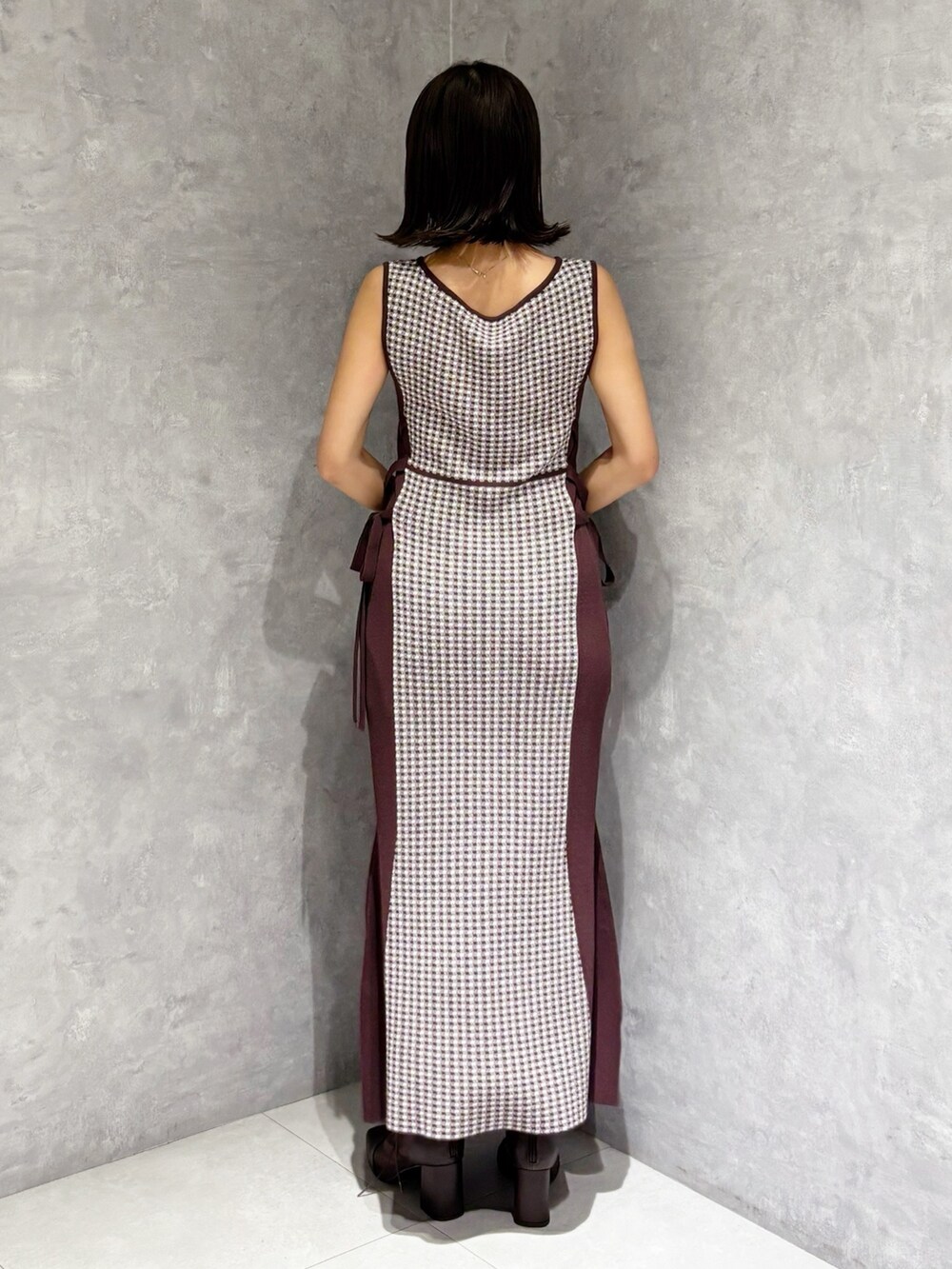 ブラウン系のワンピース、ブラウン系のブーツ、ホワイト系のハンドバッグを着用したレディースの夏コーディネートの4枚目の写真