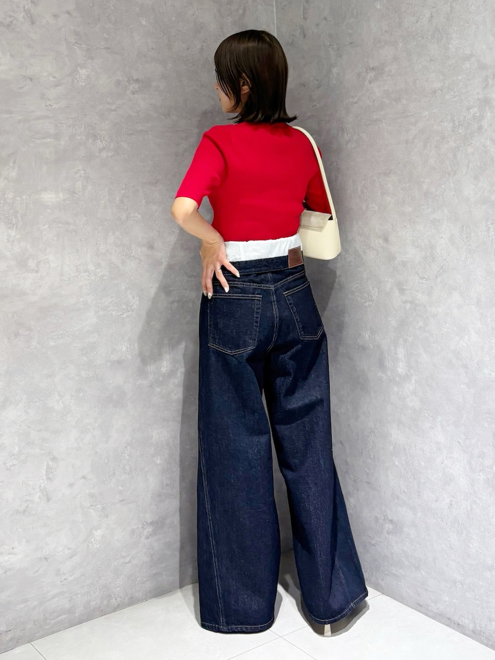 ブルー系のその他パンツ、レッド系のニット/セーター、ホワイト系のハンドバッグを着用したレディースの春コーディネートの3枚目の写真