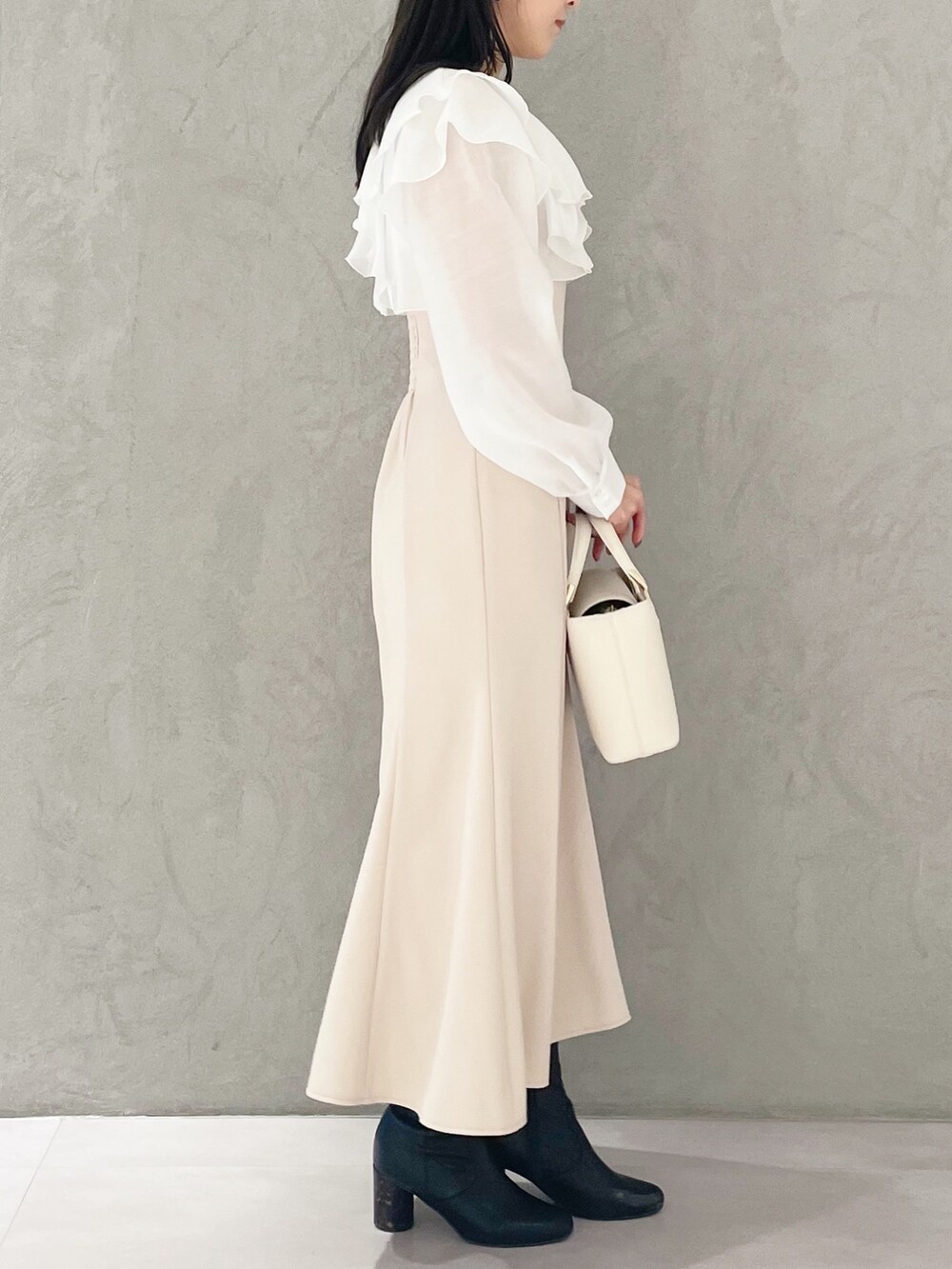 ベージュ系のワンピース、ホワイト系のハンドバッグ、ブラック系のブーツを着用したレディースの冬コーディネートの2枚目の写真