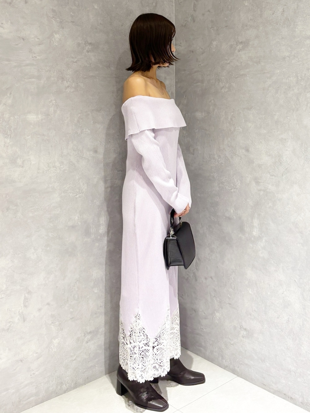 パープル系のワンピース、ブラック系のハンドバッグ、ブラウン系のブーツを着用したレディースの秋コーディネートの2枚目の写真