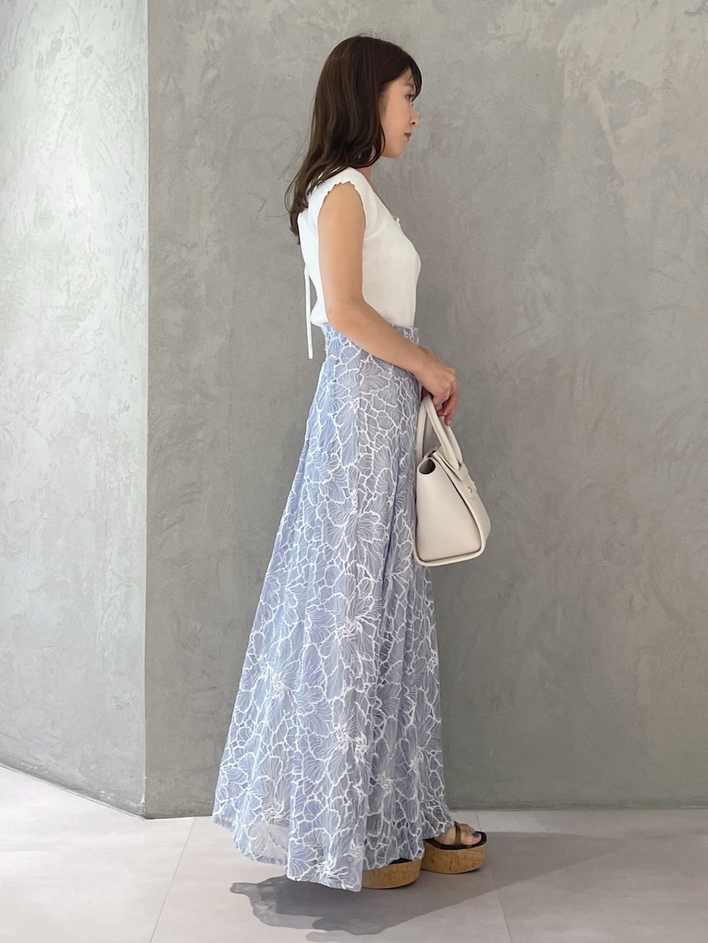 ブルー系のスカート、ブラック系のサンダル、ホワイト系のトートバッグを着用したレディースの夏コーディネートの4枚目の写真