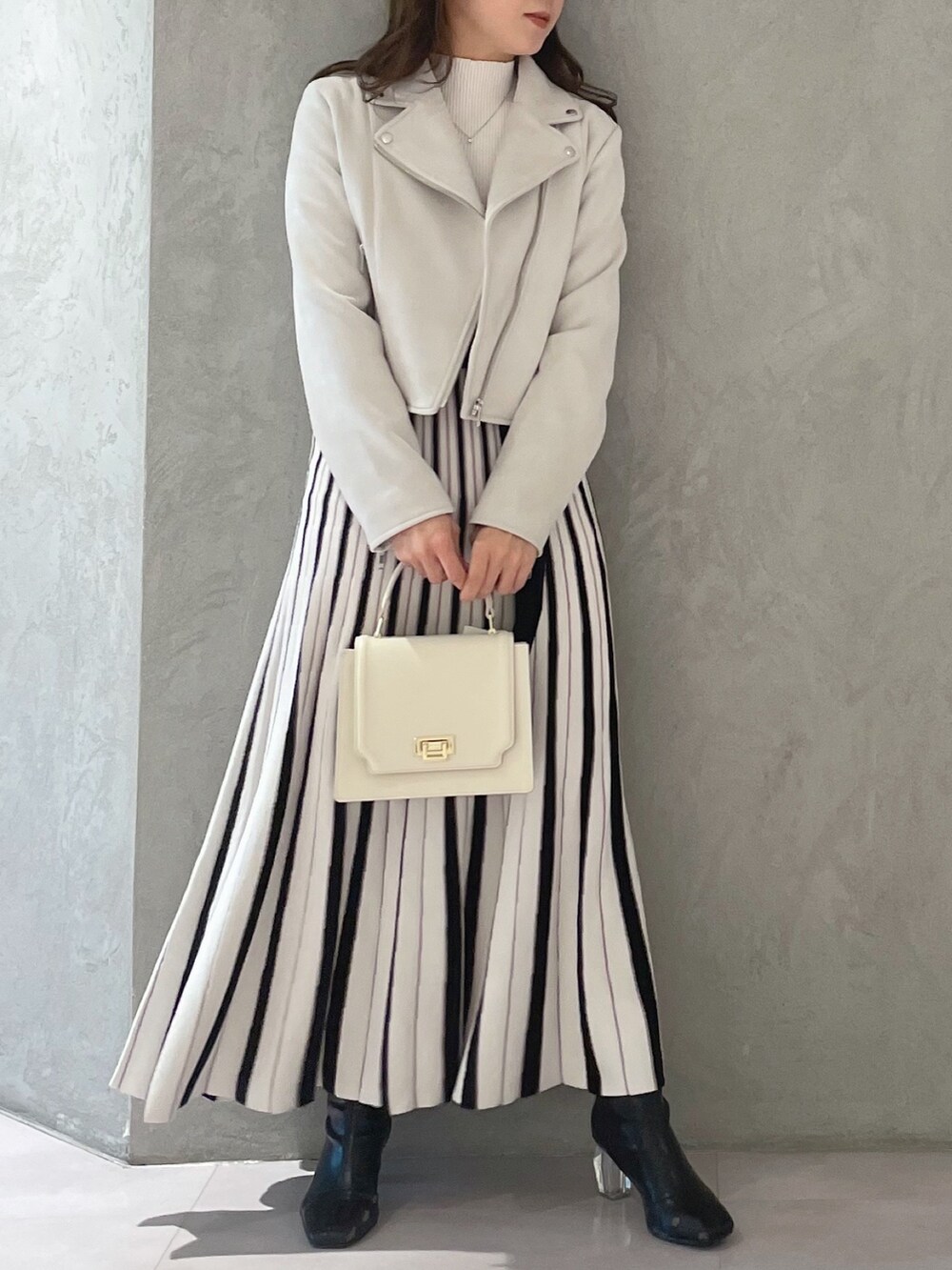 ホワイト系のワンピース、ピンク系のライダースジャケット、ホワイト系のハンドバッグを着用したレディースの春コーディネートの3枚目の写真