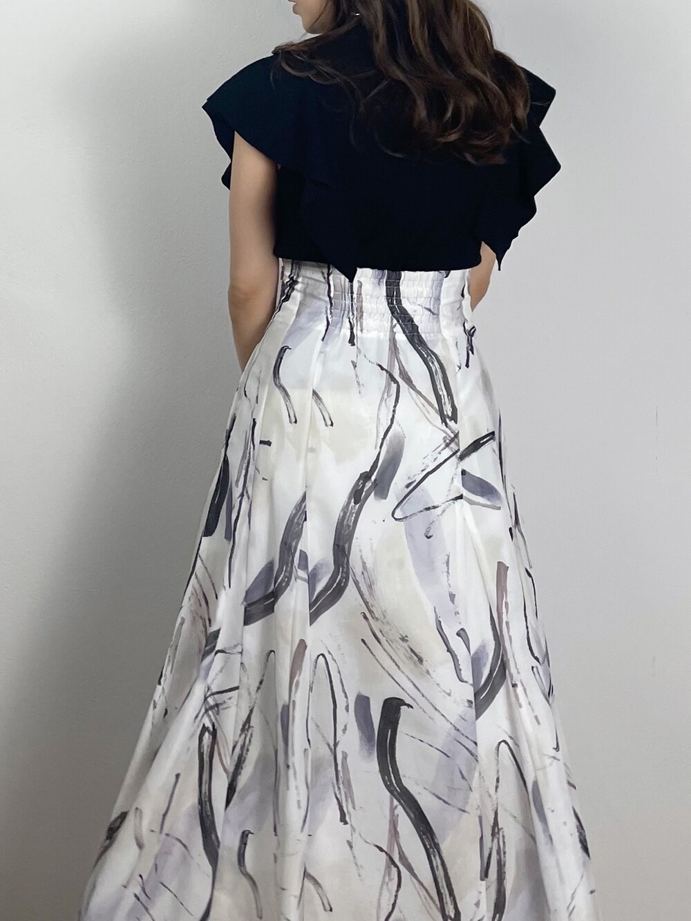 ブラック系のサンダル、ブラック系のニット/セーター、グレー系のスカートを着用したレディースの春コーディネートの5枚目の写真