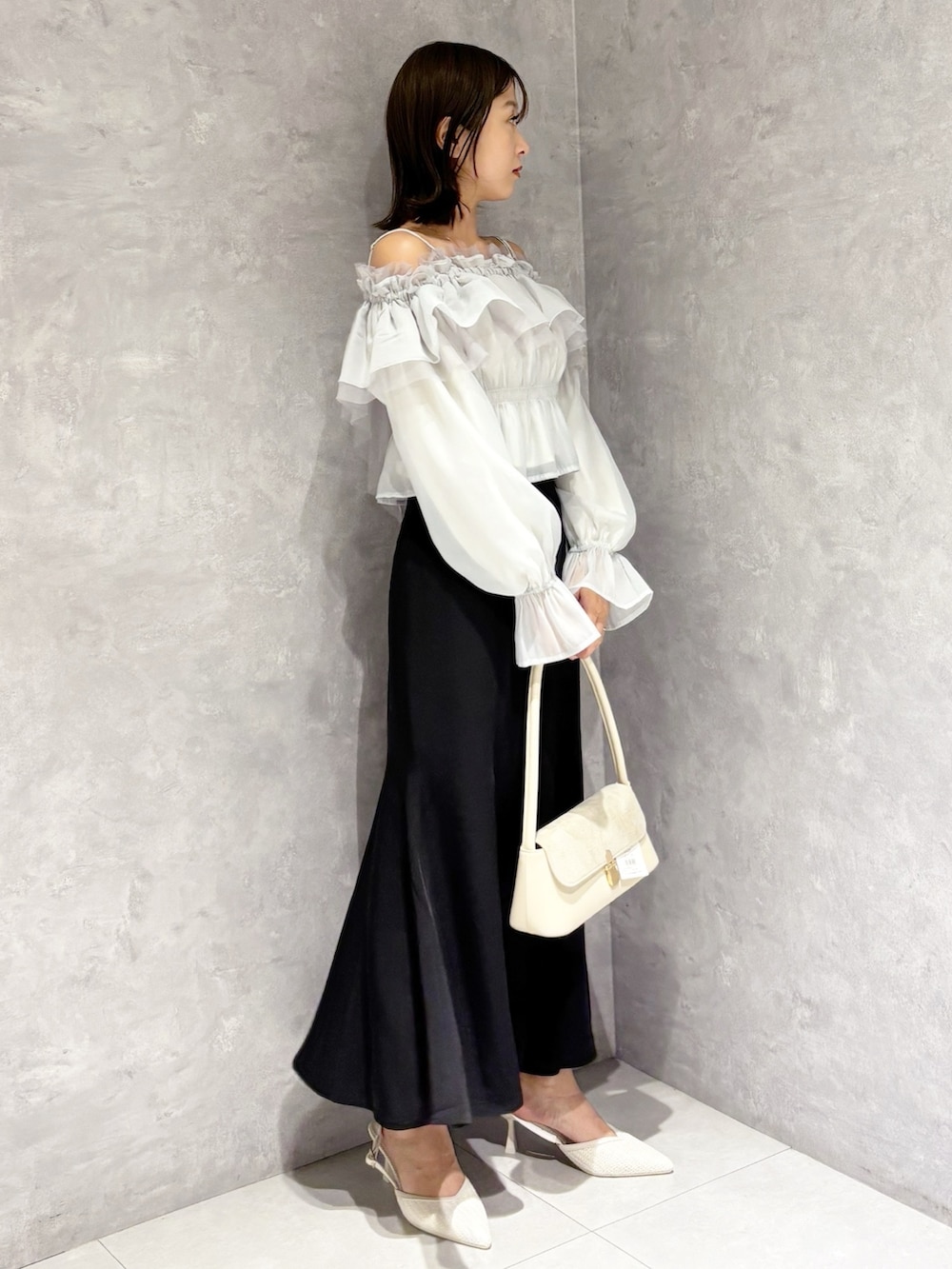 ブラック系のスカート、ホワイト系のパンプス、グリーン系のシャツ/ブラウスを着用したレディースの春コーディネートの6枚目の写真