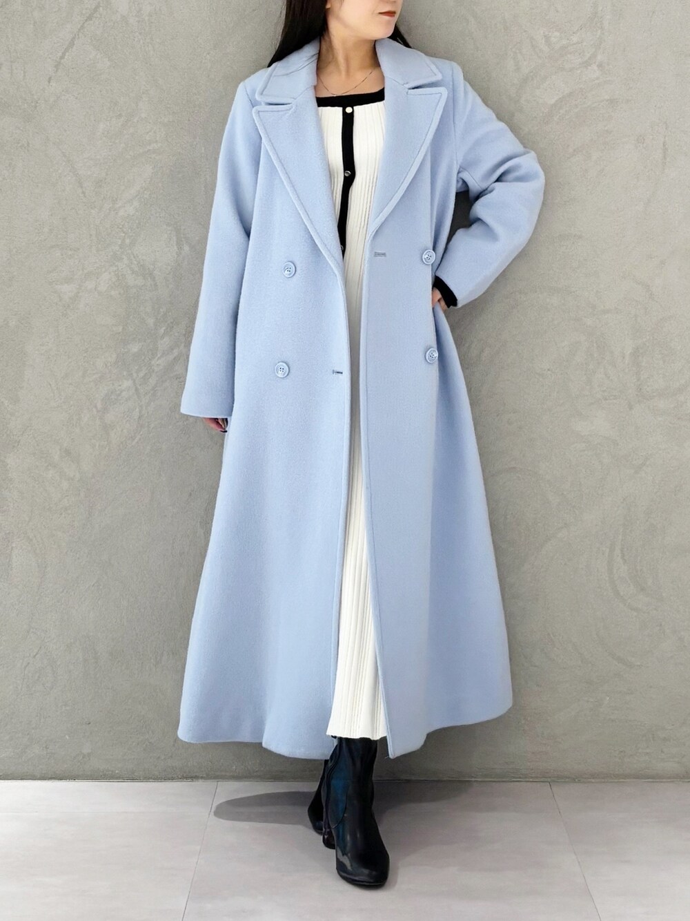 ブルー系のチェスターコート、ブラック系のブーツ、ホワイト系のワンピースを着用したレディースの冬コーディネートの9枚目の写真