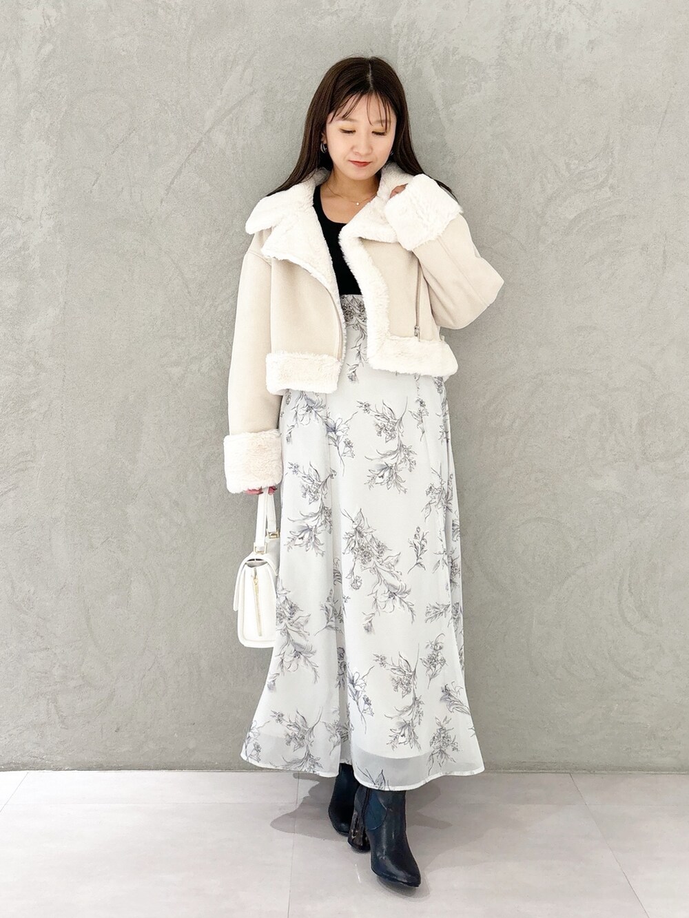 ブラック系のワンピース、ブラック系のブーツ、ホワイト系のハンドバッグを着用したレディースの秋コーディネートの9枚目の写真