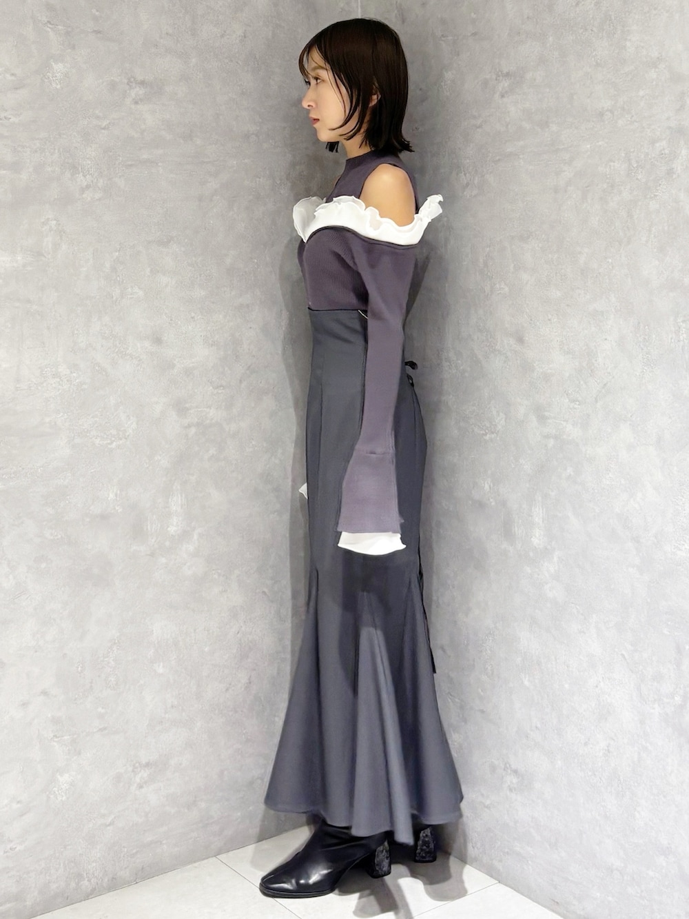 グレー系のスカート、グレー系のニット/セーター、ブラック系のブーツを着用したレディースの冬コーディネートの5枚目の写真