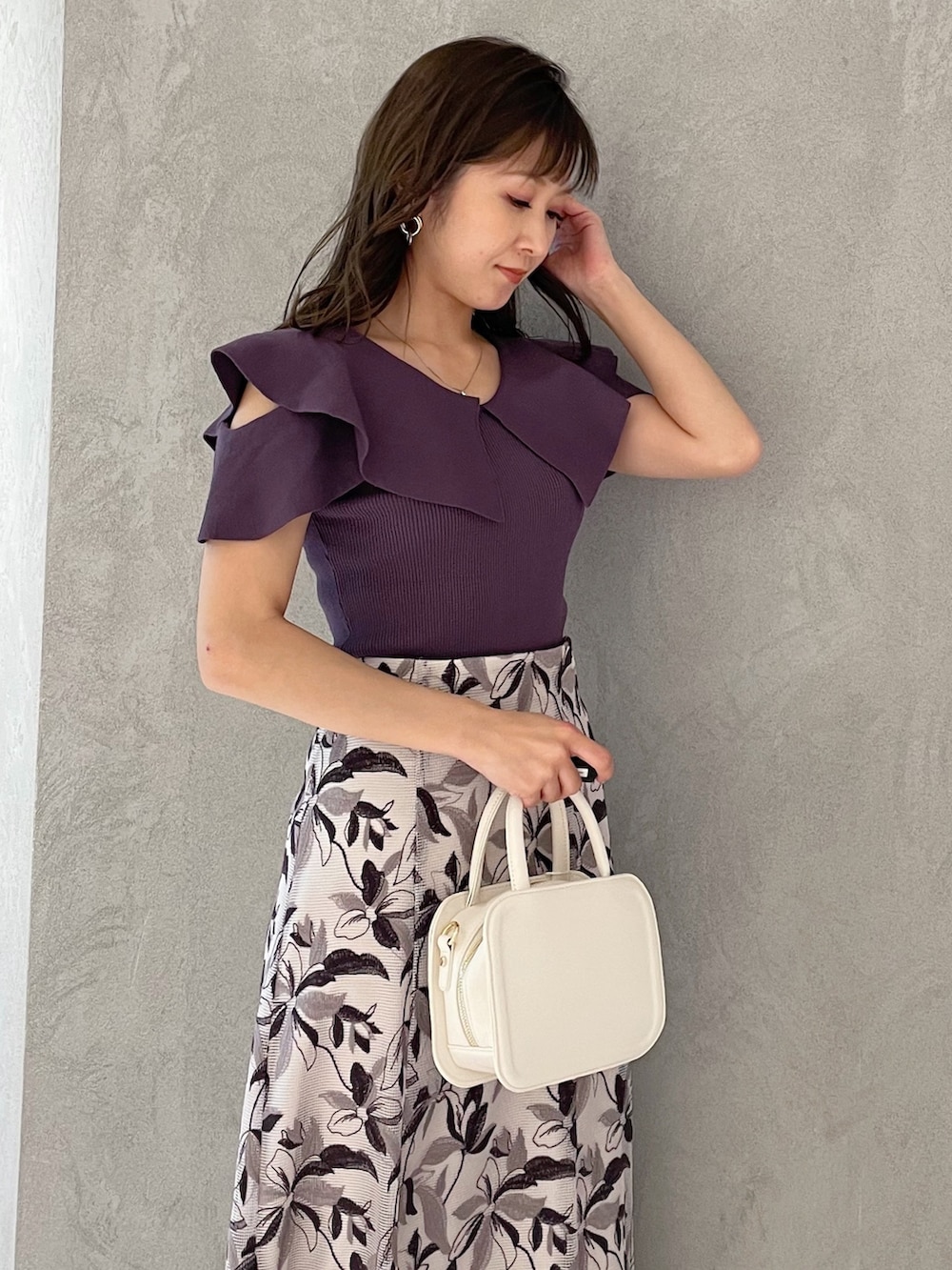ホワイト系のハンドバッグ、ブラック系のサンダル、パープル系のニット/セーターを着用したレディースの春コーディネートの4枚目の写真