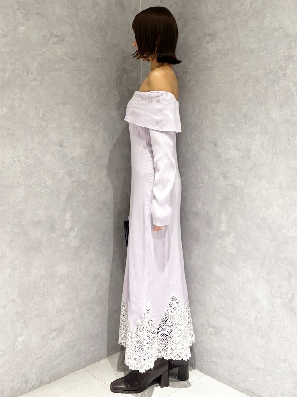 パープル系のワンピース、ブラック系のハンドバッグ、ブラウン系のブーツを着用したレディースの秋コーディネートの4枚目の写真