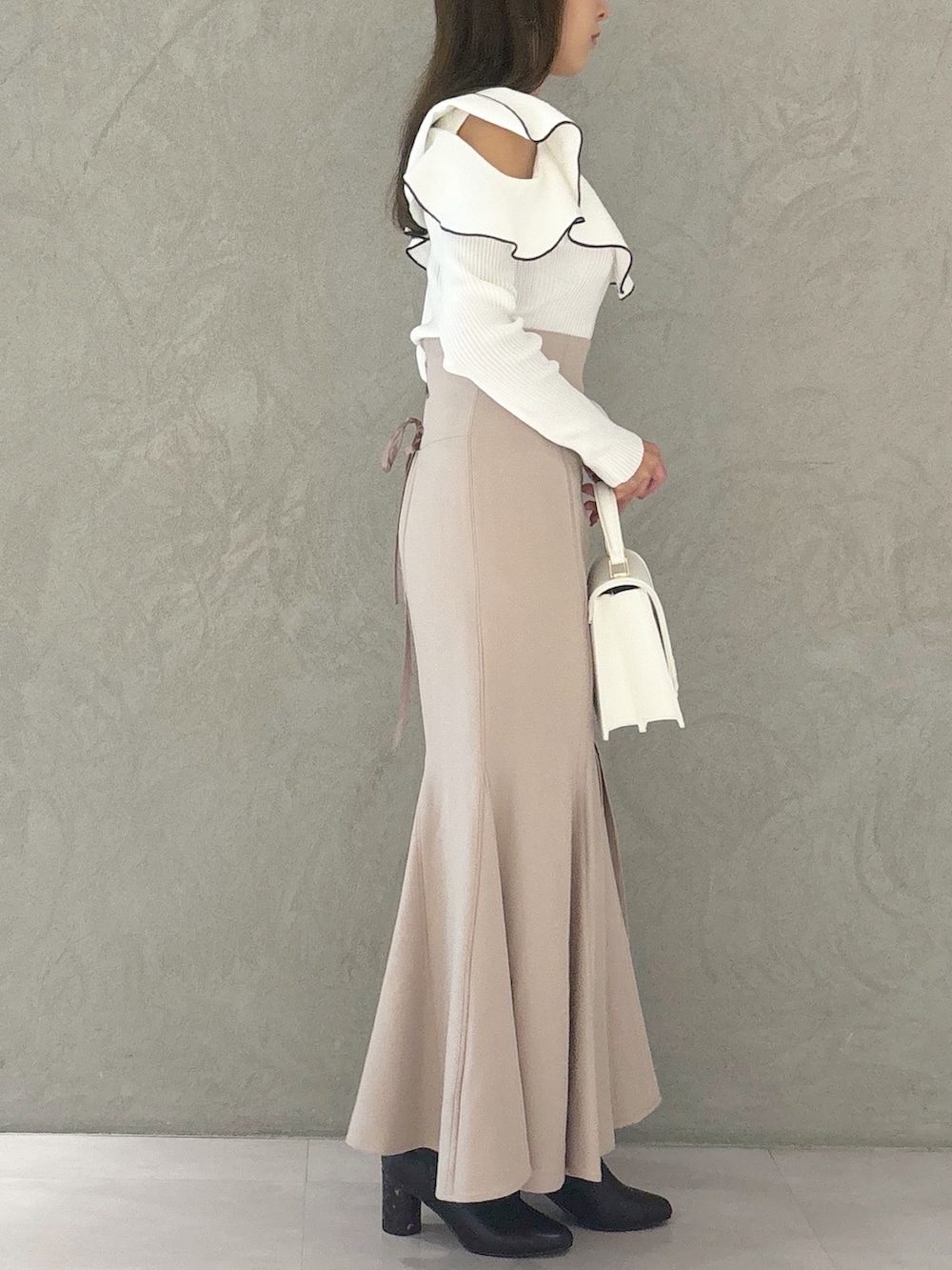 ピンク系のスカート、ブラック系のブーツ、ホワイト系のハンドバッグを着用したレディースの秋コーディネートの4枚目の写真