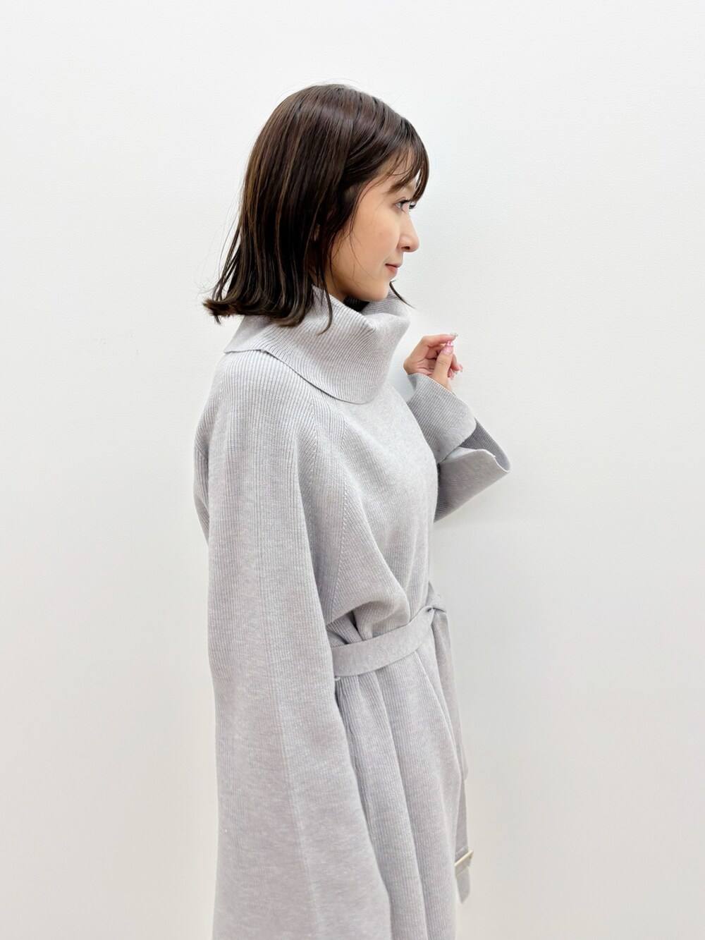 グレー系のニット/セーター、グレー系のブーツ、ホワイト系のスカートを着用したレディースの秋コーディネートの4枚目の写真