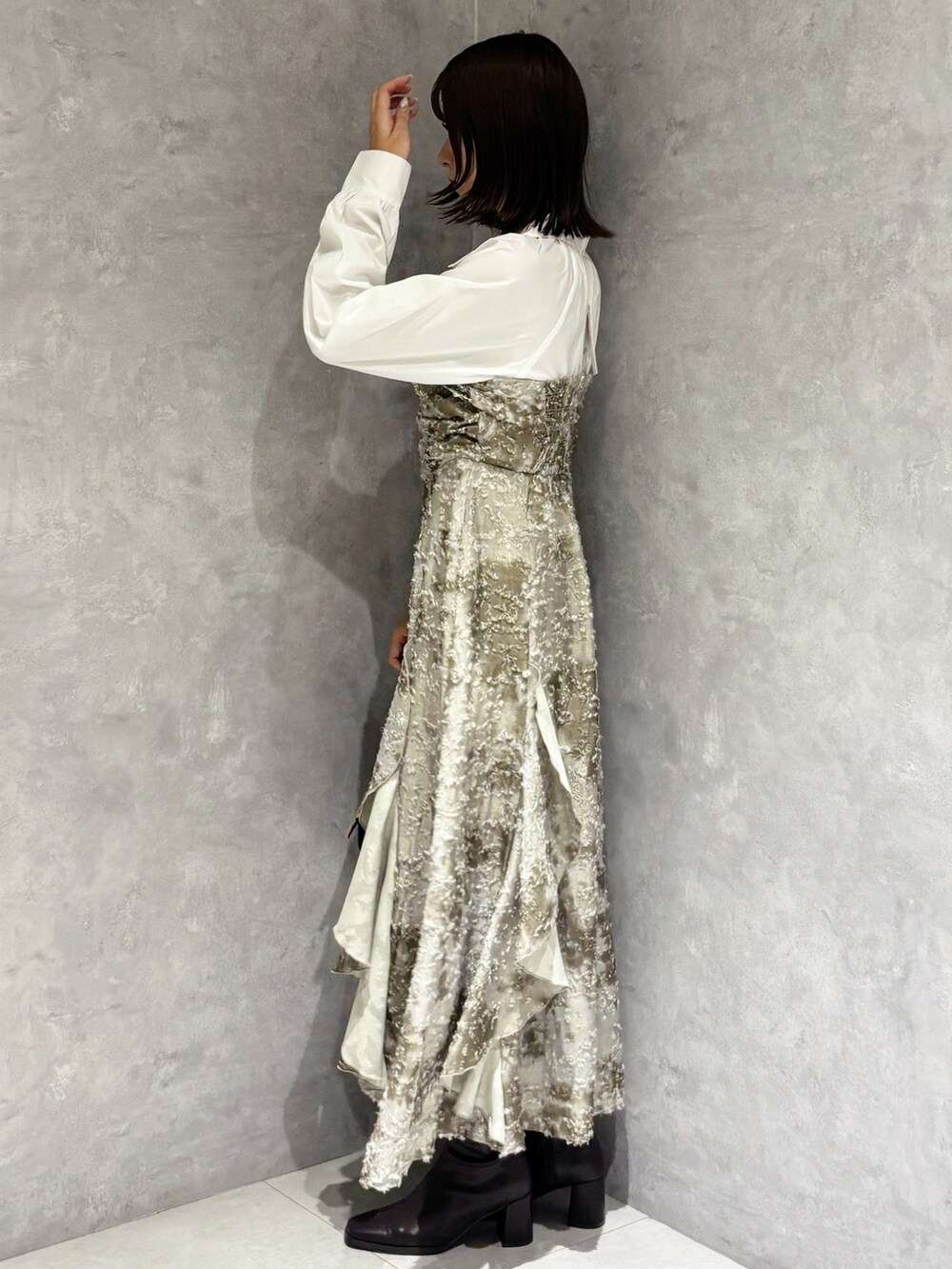 ブラック系のハンドバッグ、ブラウン系のブーツ、グリーン系のワンピースを着用したレディースの秋コーディネートの2枚目の写真