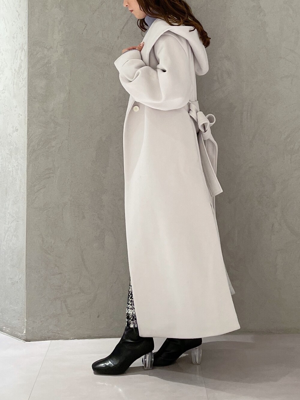 ブルー系のニット/セーター、ブラック系のスカート、ホワイト系のチェスターコートを着用したレディースの冬コーディネートの7枚目の写真