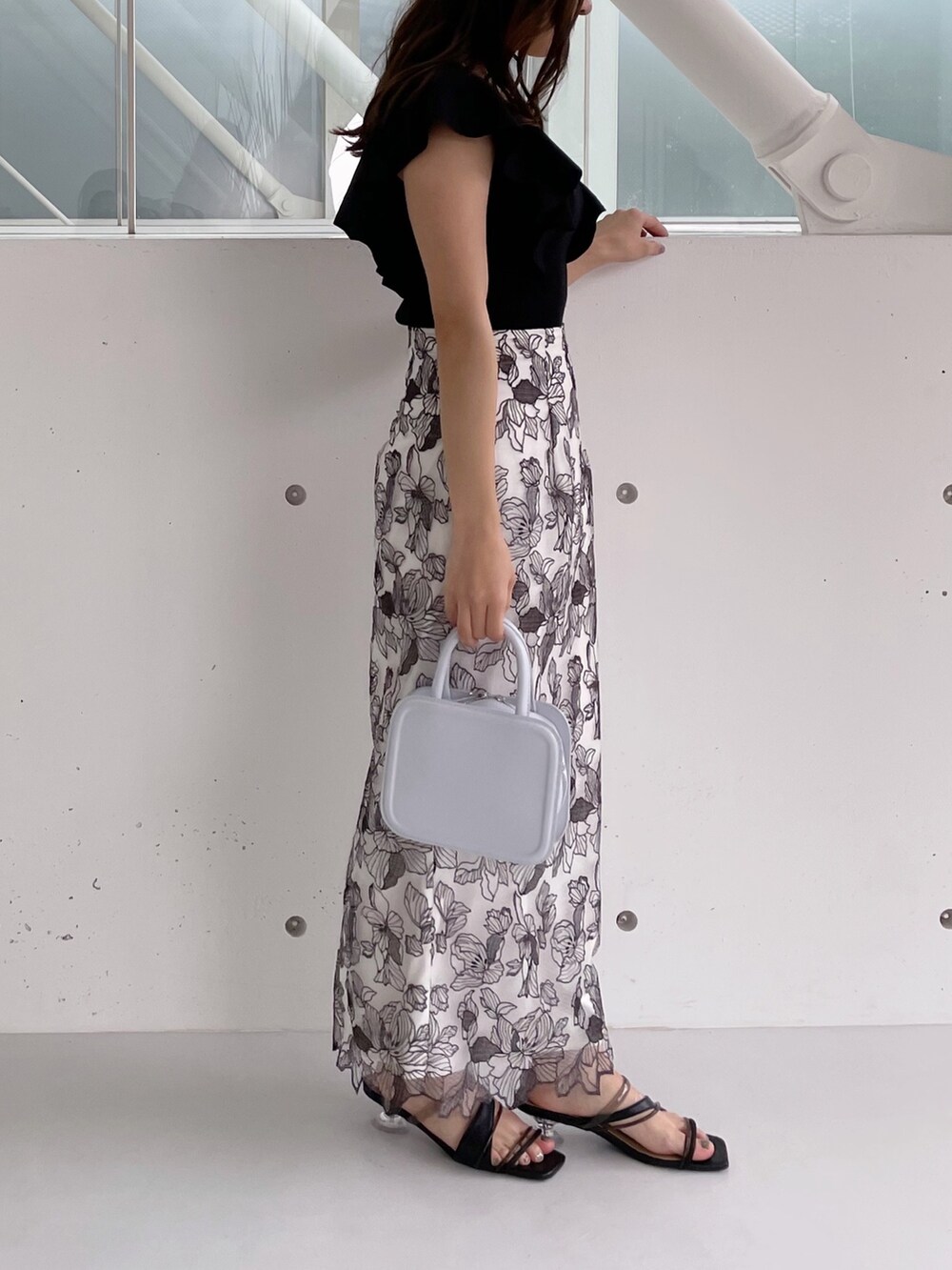 ホワイト系のスカート、ブラック系のニット/セーター、ブラック系のサンダルを着用したレディースの冬コーディネートの5枚目の写真