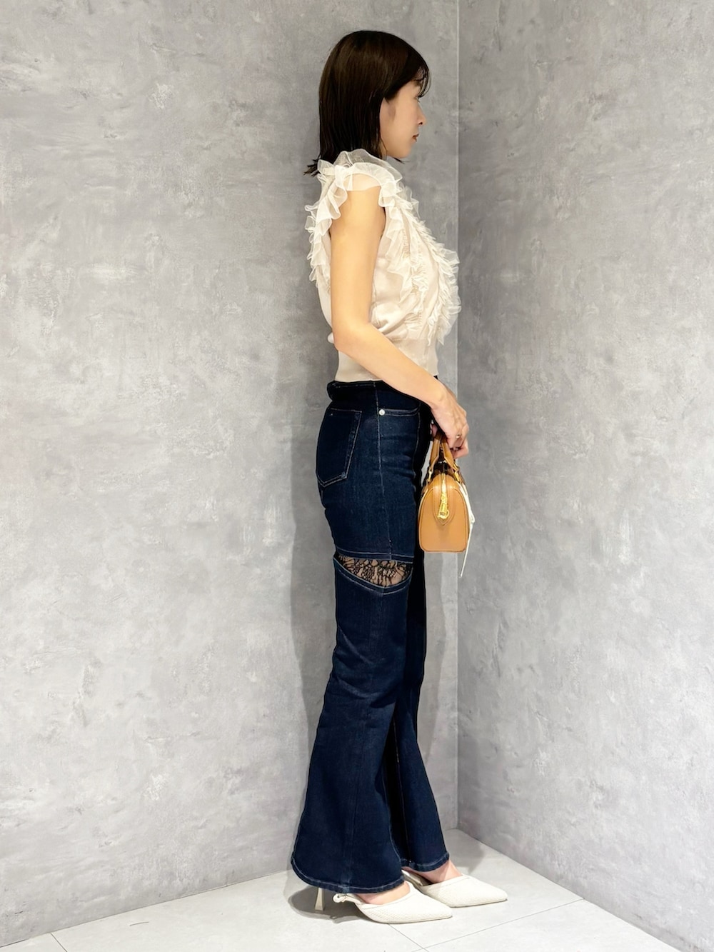 ブルー系のデニムパンツ、ピンク系のニット/セーター、ホワイト系のパンプスを着用したレディースの春コーディネートの4枚目の写真