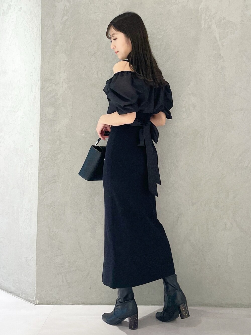 ブラック系のハンドバッグ、ブラック系のブーツ、ブラック系のワンピースを着用したレディースの春コーディネートの2枚目の写真