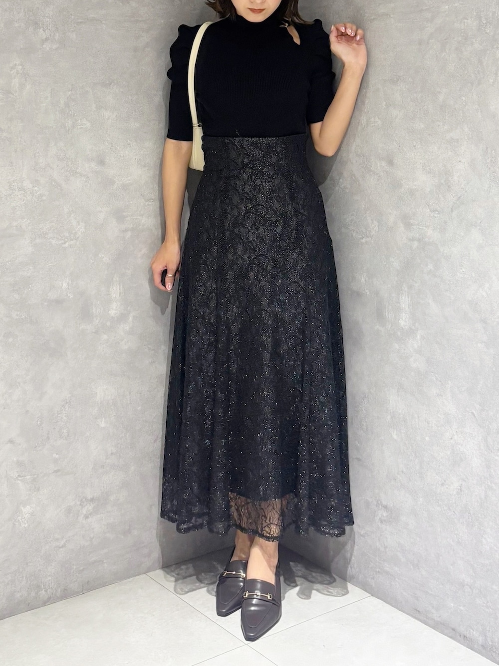 ブラック系のスカート、ブラック系のニット/セーター、ホワイト系のハンドバッグを着用したレディースの春コーディネートの4枚目の写真