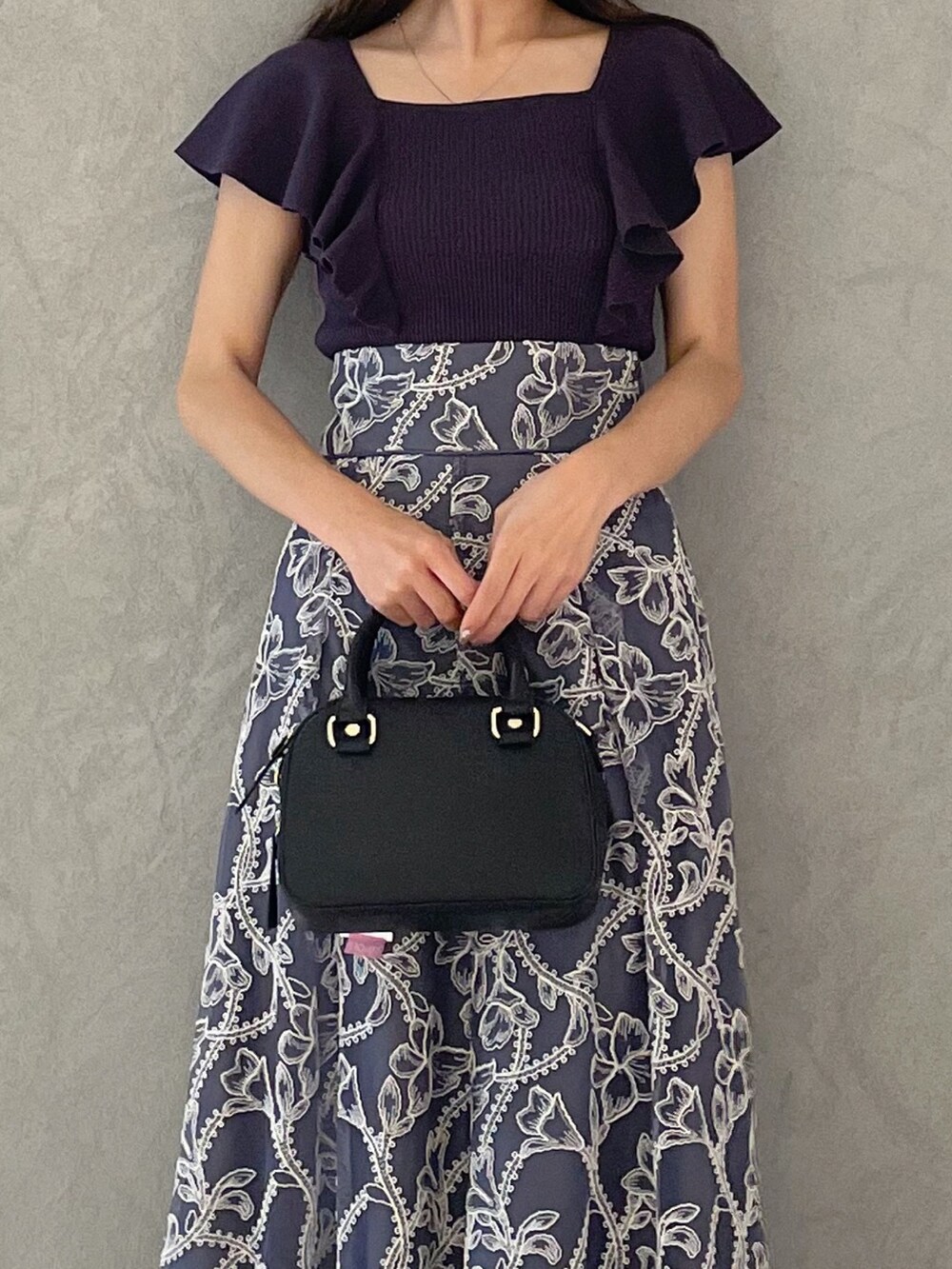 グレー系のスカート、グレー系のニット/セーター、ブラック系のサンダルを着用したレディースの夏コーディネートの4枚目の写真