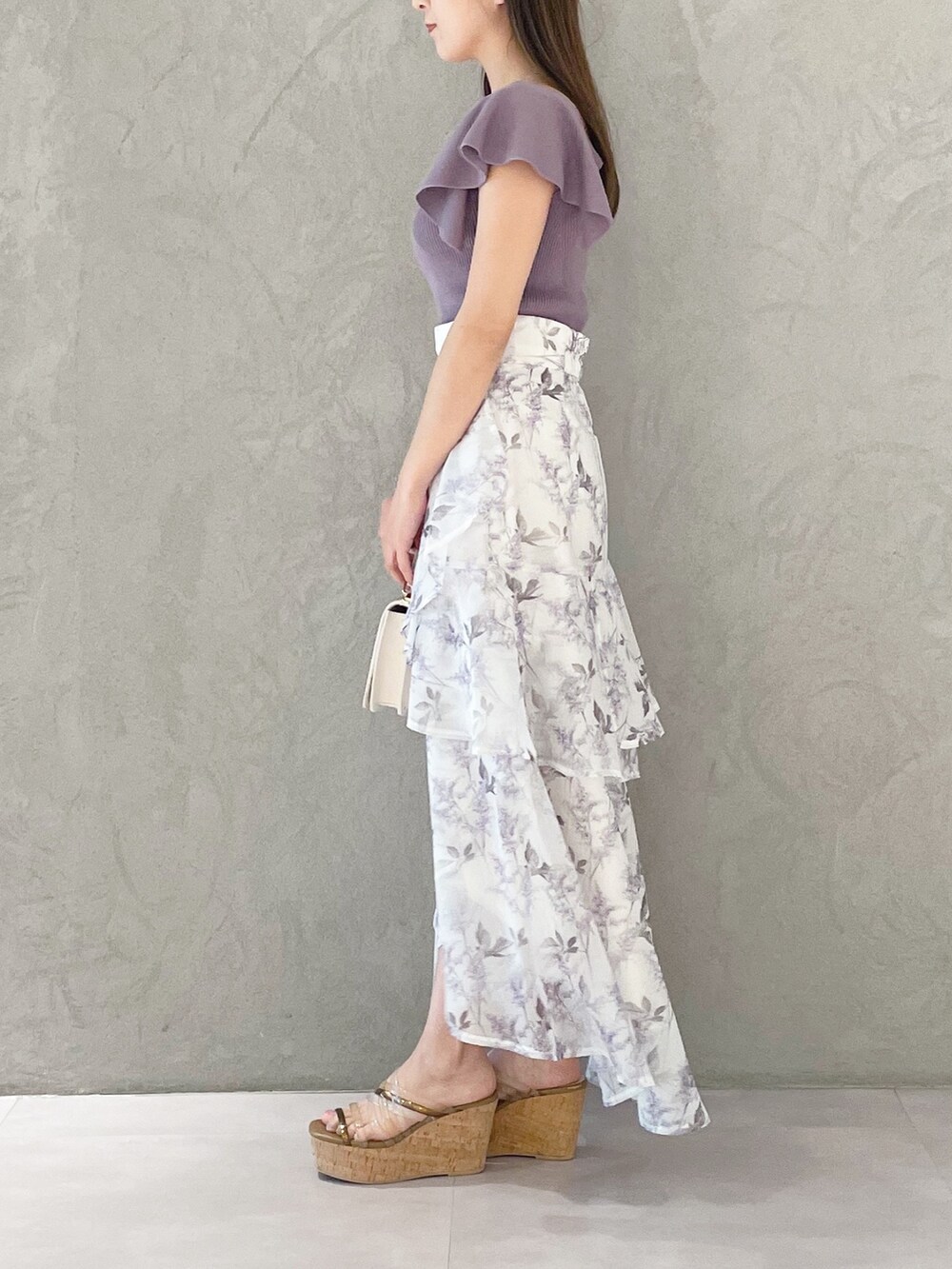 ホワイト系のハンドバッグ、パープル系のスカート、ブラウン系のサンダルを着用したレディースの春コーディネートの5枚目の写真