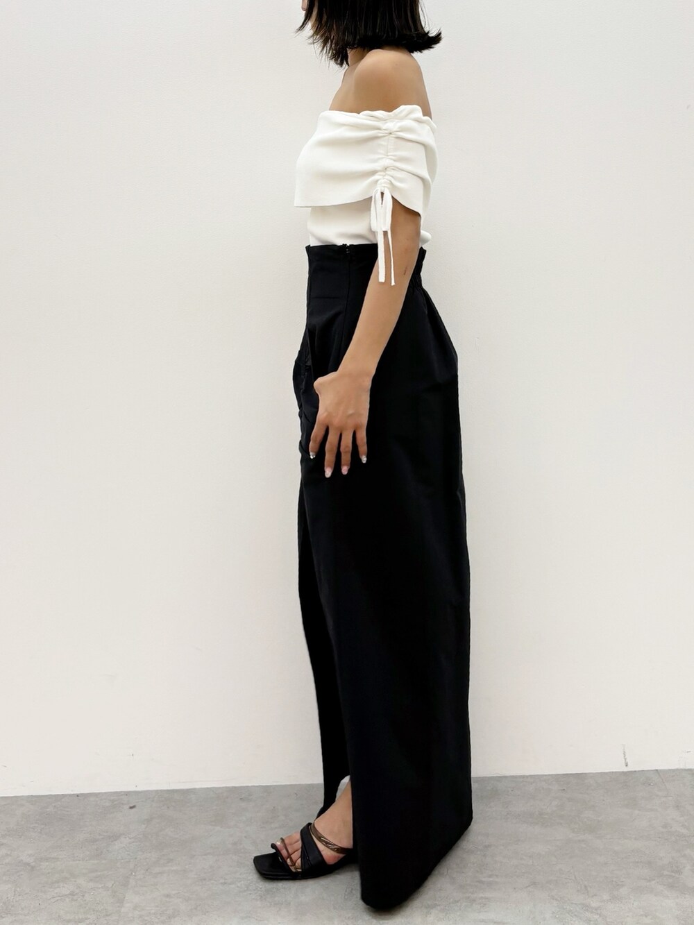 ブラック系のスカート、ホワイト系のニット/セーターを着用したレディースの夏コーディネートの4枚目の写真