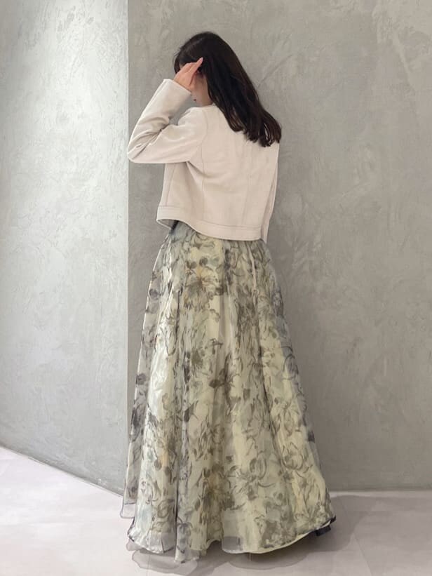 グレー系のライダースジャケット、イエロー系のスカート、ホワイト系のニット/セーターを着用したレディースの秋コーディネートの4枚目の写真